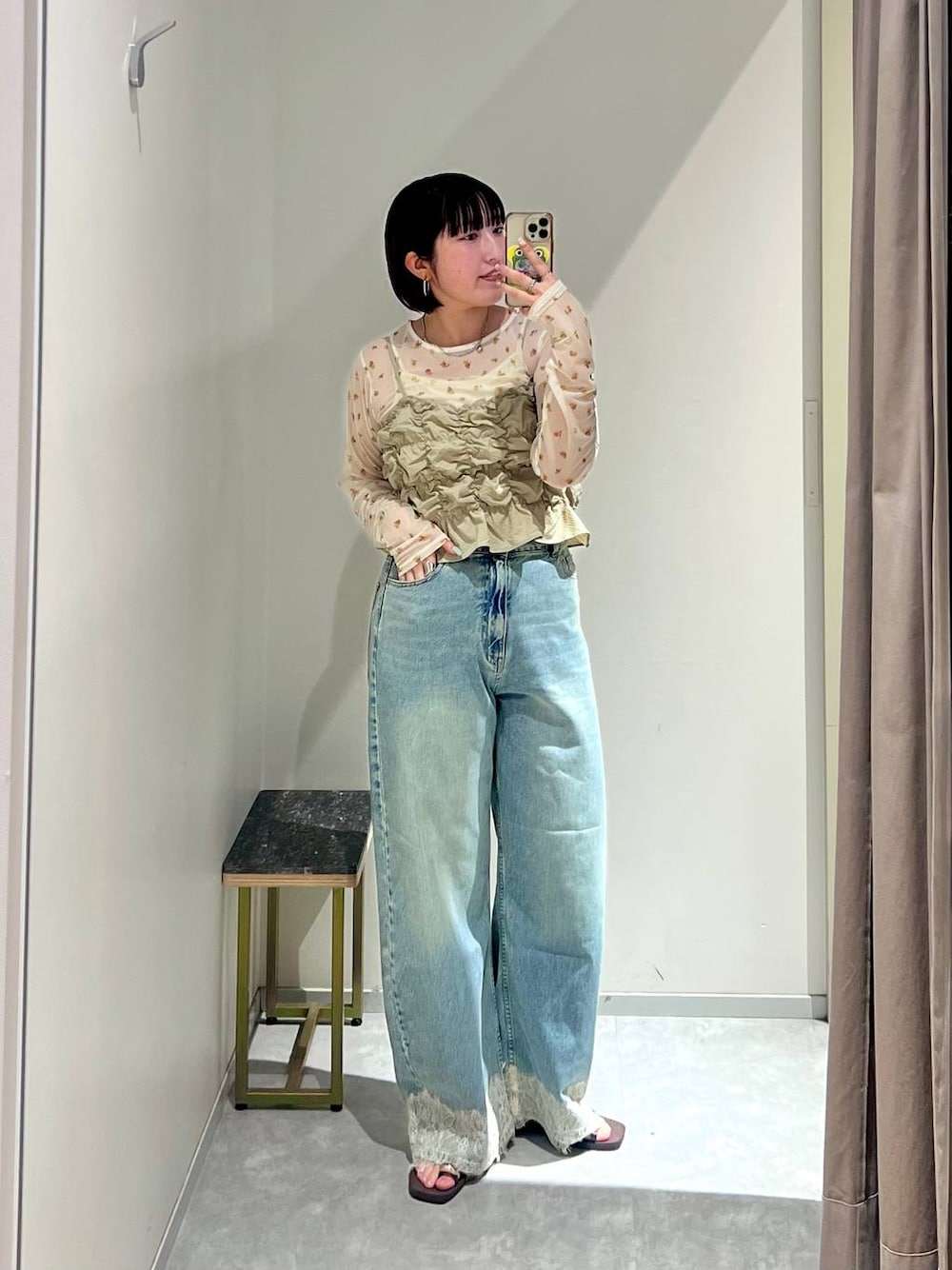 ベージュ系のベスト、ブルー系のデニムパンツ、ブラウン系のサンダルを着用したレディースの夏コーディネートの1枚目の写真