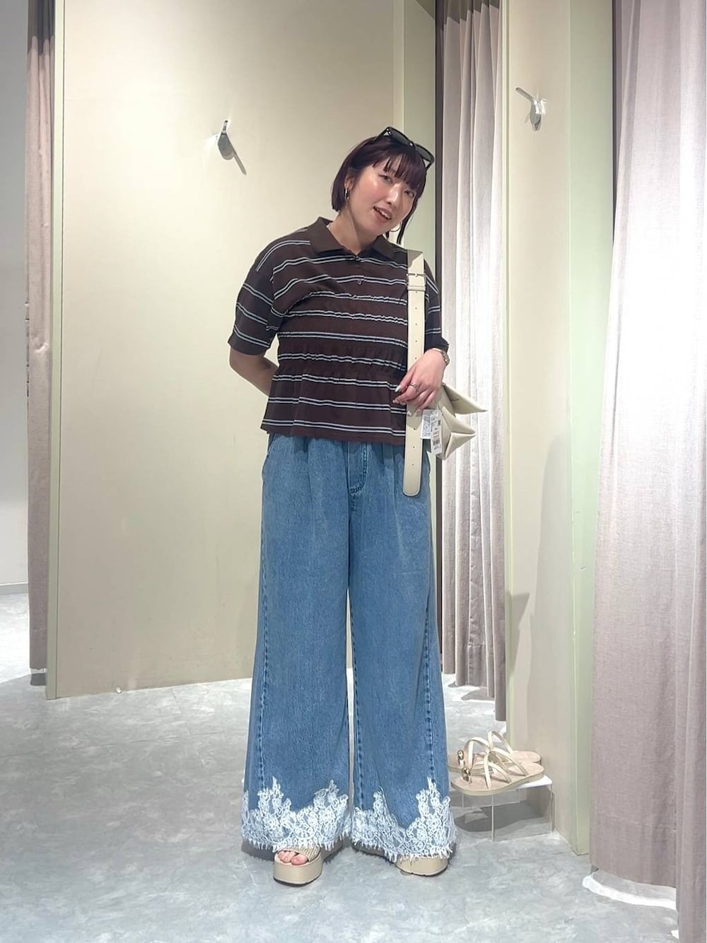 ホワイト系のショルダーバッグ、ブルー系のデニムパンツ、ホワイト系のサンダルを着用したレディースの夏コーディネートの1枚目の写真