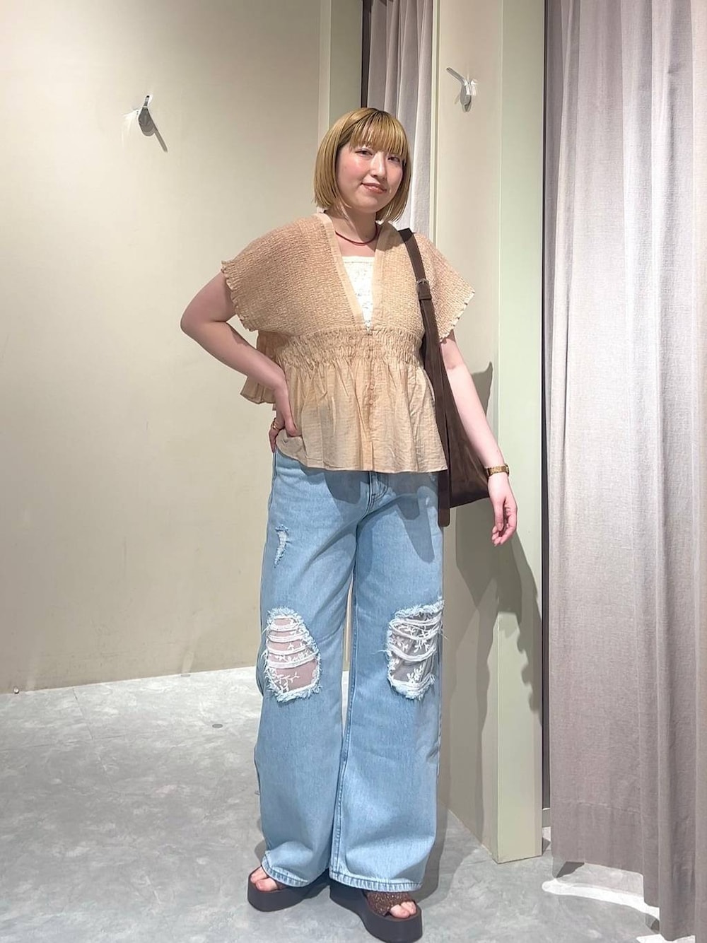 ブラウン系のショルダーバッグ、ブルー系のデニムパンツ、ブラウン系のサンダルを着用したレディースの春コーディネートの1枚目の写真
