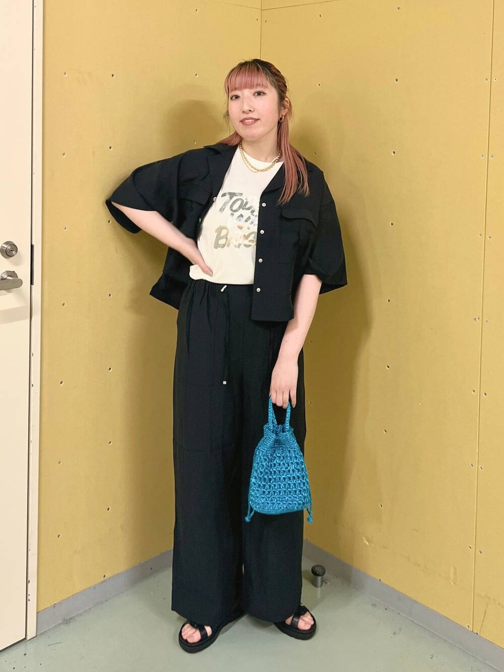 ブラック系のスニーカー、ホワイト系のTシャツ/カットソー、ブルー系のショルダーバッグを着用したレディースの春コーディネートの1枚目の写真
