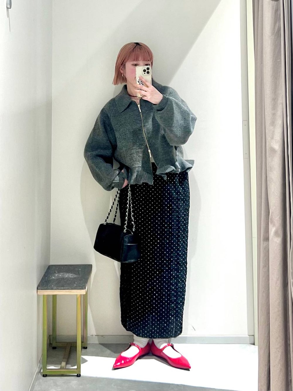 レッド系のパンプス、ブラック系のショルダーバッグ、ブラック系のスカートを着用したレディースの冬コーディネートの1枚目の写真