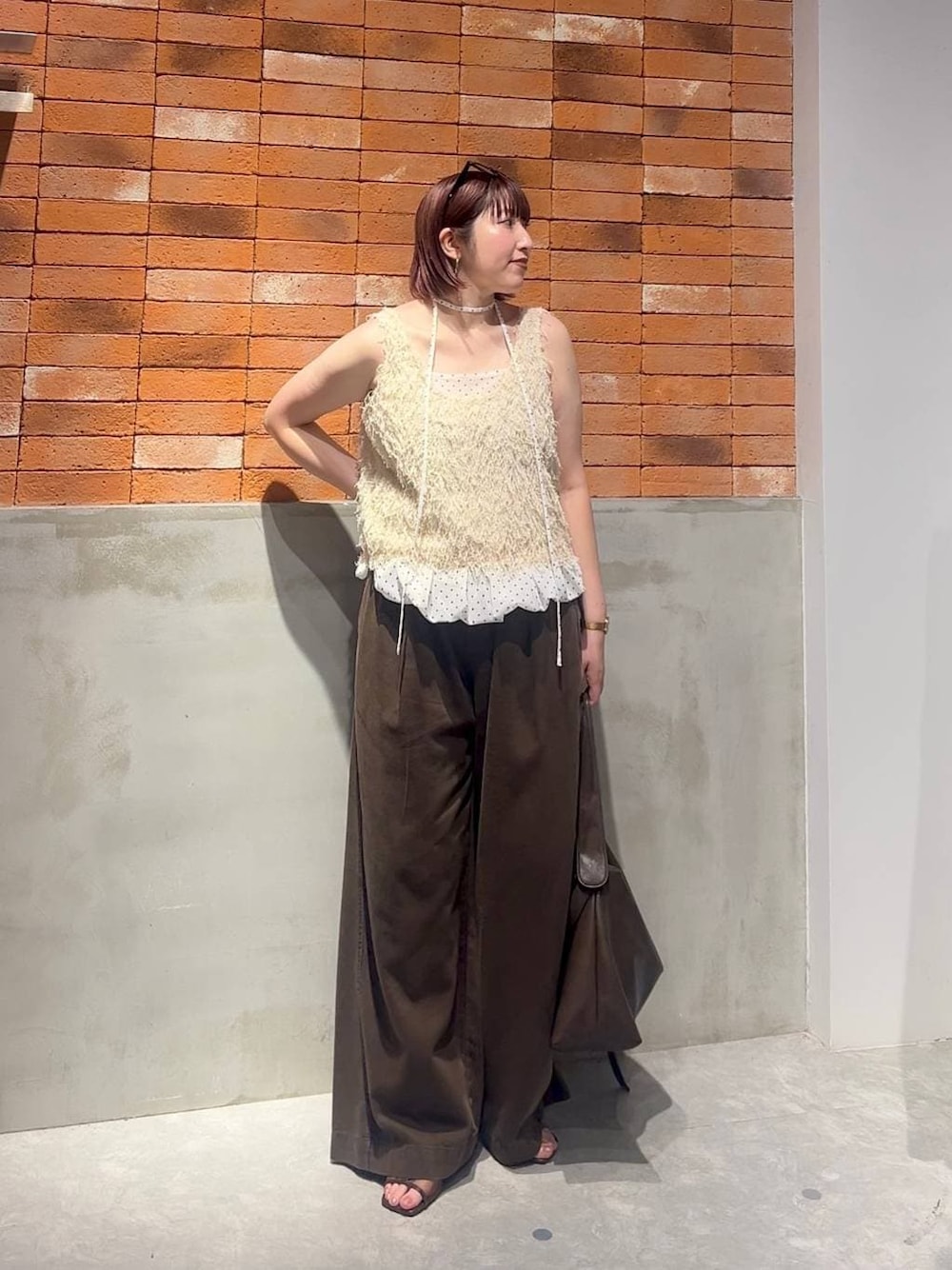 ブラウン系のショルダーバッグ、ブラウン系のサンダル、ホワイト系のベストを着用したレディースの夏コーディネートの1枚目の写真