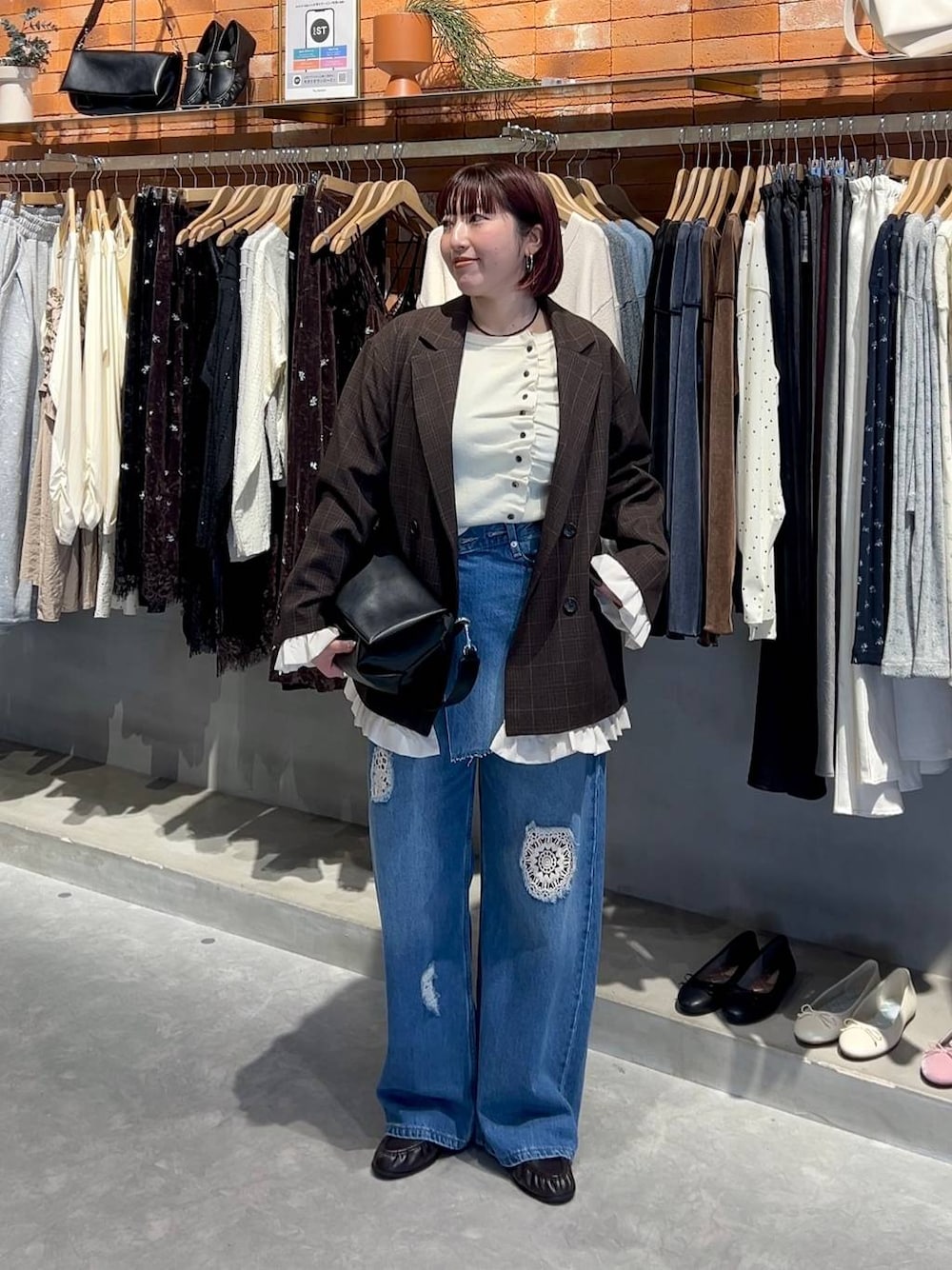 ブラック系のショルダーバッグ、ブルー系のデニムパンツ、ホワイト系のニット/セーターを着用したレディースの秋コーディネートの1枚目の写真