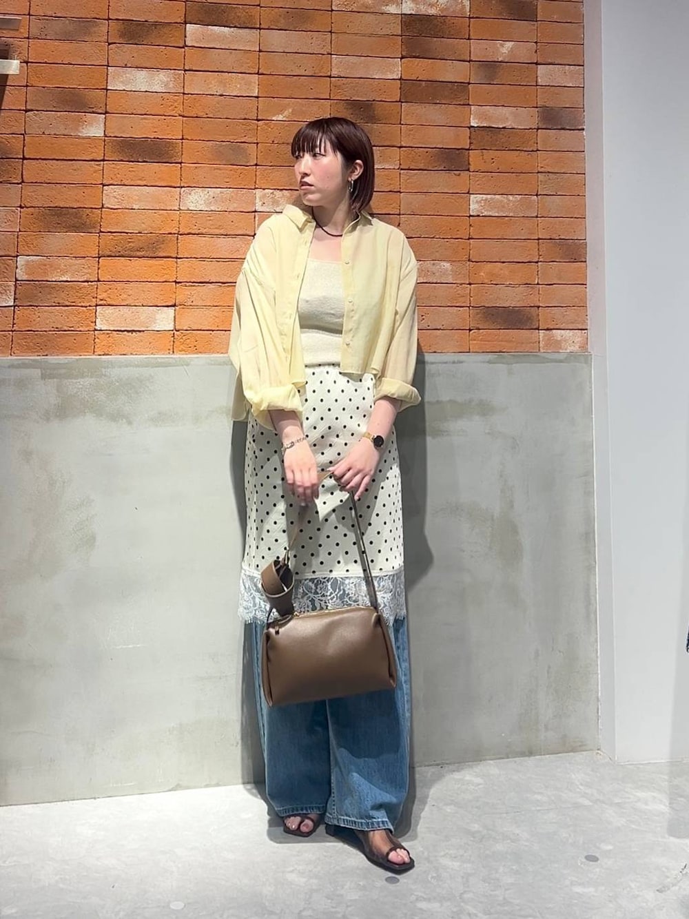 ゴールド系のタンクトップ、イエロー系のシャツ/ブラウス、ブルー系のデニムパンツを着用したレディースの夏コーディネートの1枚目の写真