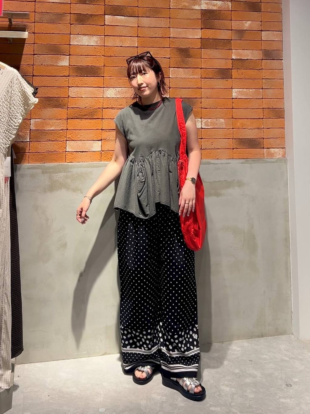 グレー系のTシャツ/カットソー、シルバー系のサンダル、レッド系のショルダーバッグを着用したレディースの夏コーディネートの1枚目の写真