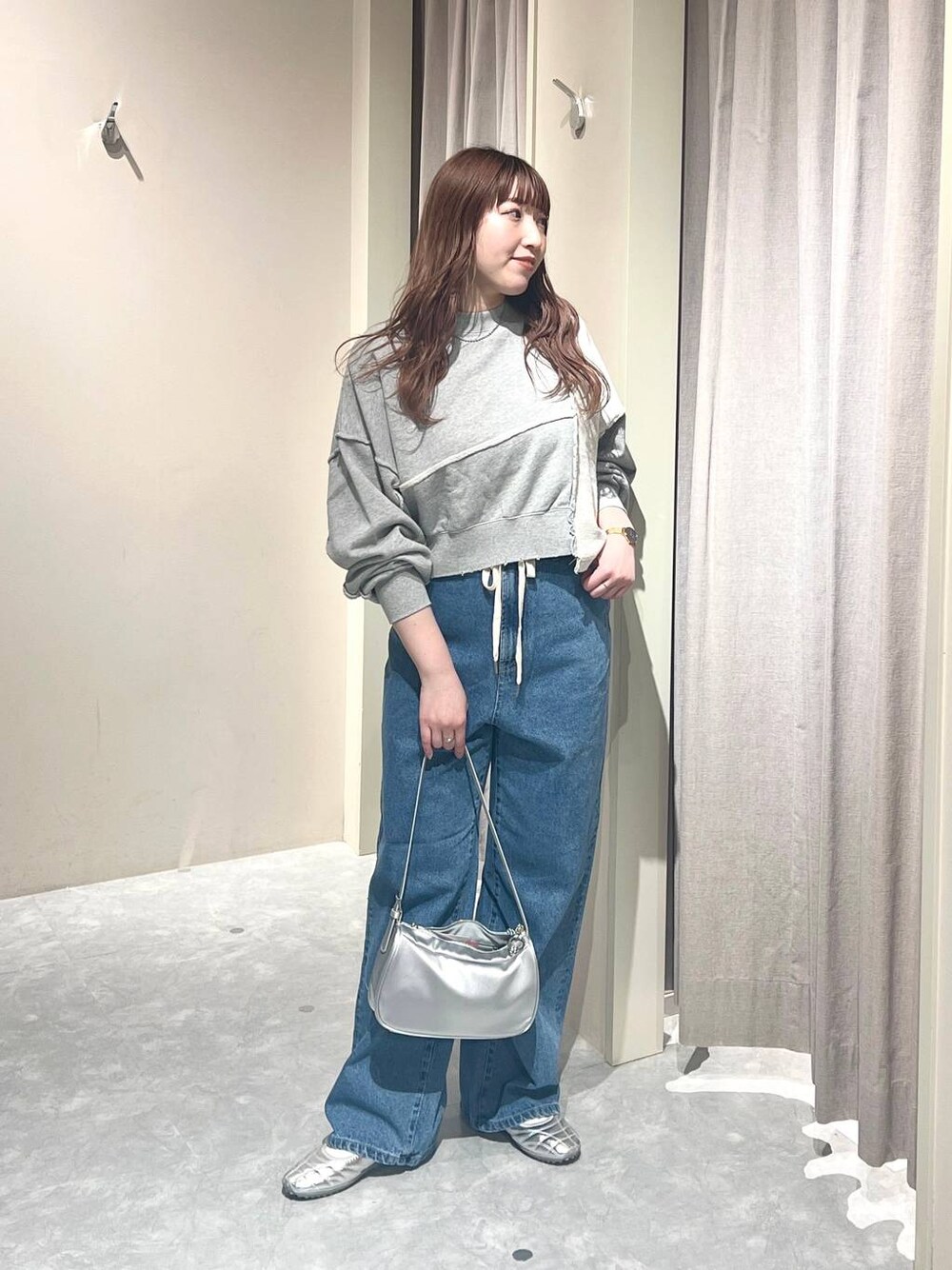 グレー系のスウェット、ブルー系のデニムパンツ、シルバー系のトートバッグを着用したレディースの春コーディネートの1枚目の写真