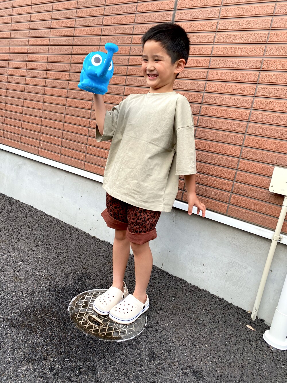 ブラウン系のパンツ、ホワイト系のサンダル、ベージュ系のTシャツ/カットソーを着用したキッズの夏コーディネートの1枚目の写真