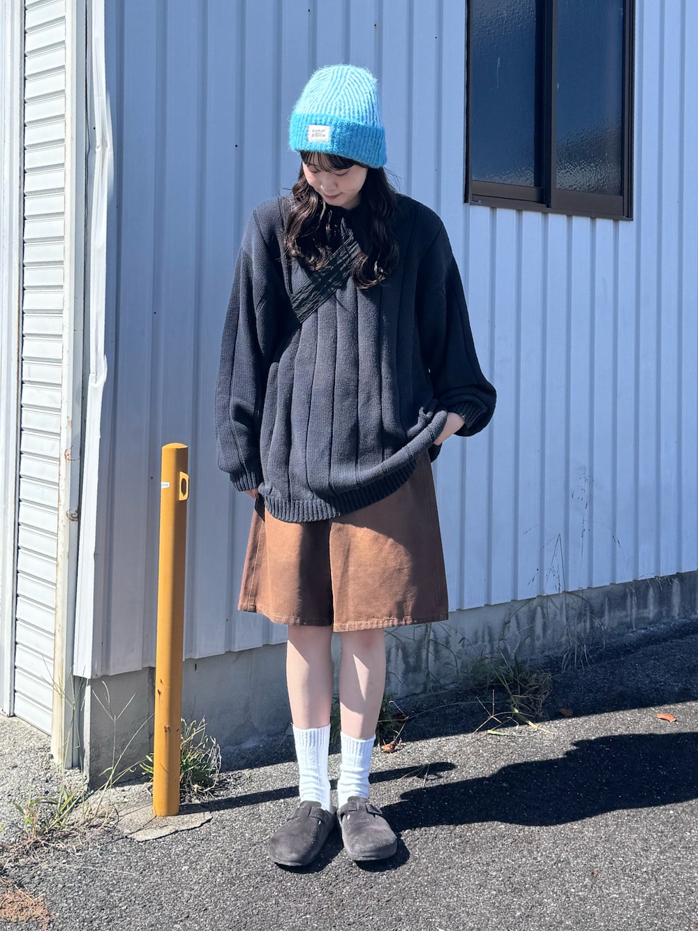 グレー系のサンダル、ブラウン系のデニムパンツ、ブルー系のニット/セーターを着用したレディースの秋コーディネートの1枚目の写真