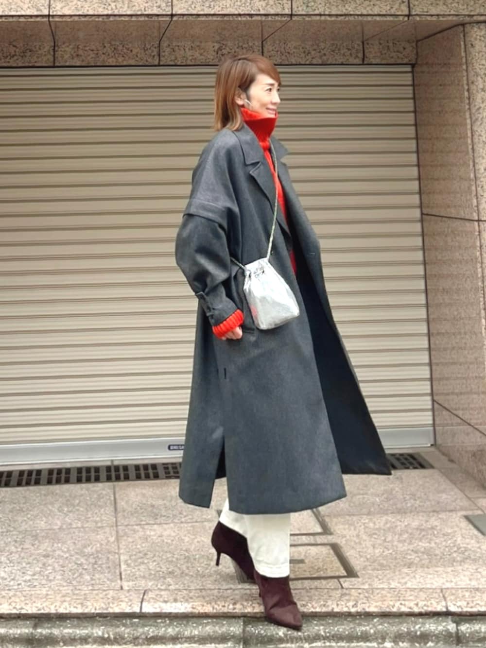 グレー系のチェスターコート、オレンジ系のニット/セーター、ホワイト系のその他パンツを着用したレディースの冬コーディネートの1枚目の写真