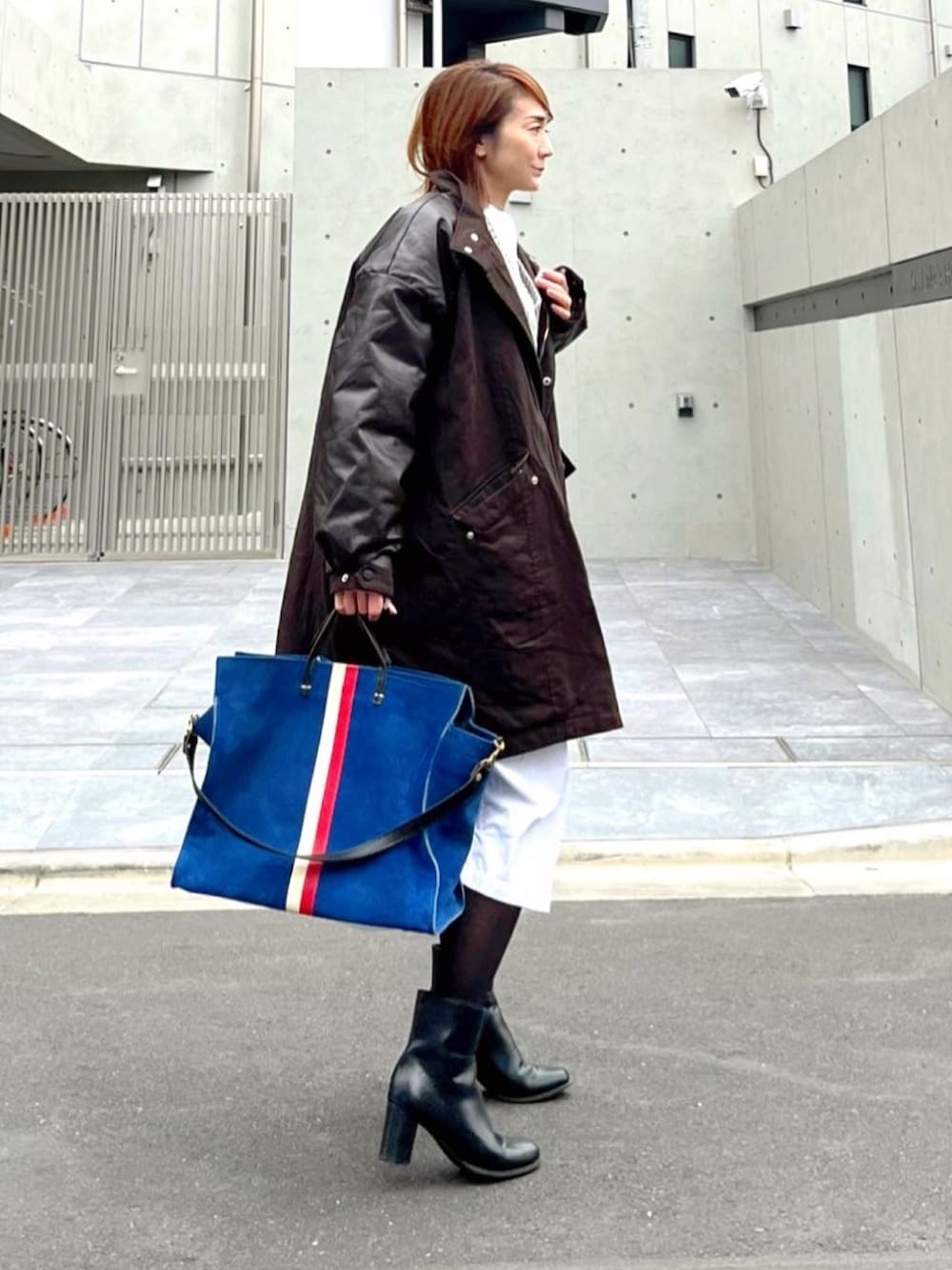 ブラウン系のミリタリージャケット、ブルー系のトートバッグ、ホワイト系のシャツワンピースを着用したレディースの冬コーディネートの1枚目の写真