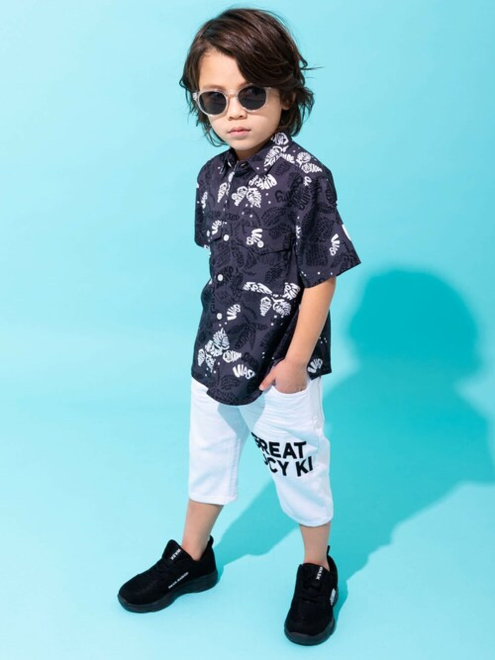 「柄シャツ、ハーフパンツ、デニムパンツ、ロゴプリント、男の子、ボタニカル柄、リゾートスタイル、アロハシャツ、WASK、ワスク」｜「WASKのWASK ロゴ ボタニカル柄 ワイド シャツ (100~160cm)（シャツ/ブラウス、ブラック系）」を使った、BEBE ONLINE STOREさん（キッズ・109cm）の春コーディネートの1枚目の写真