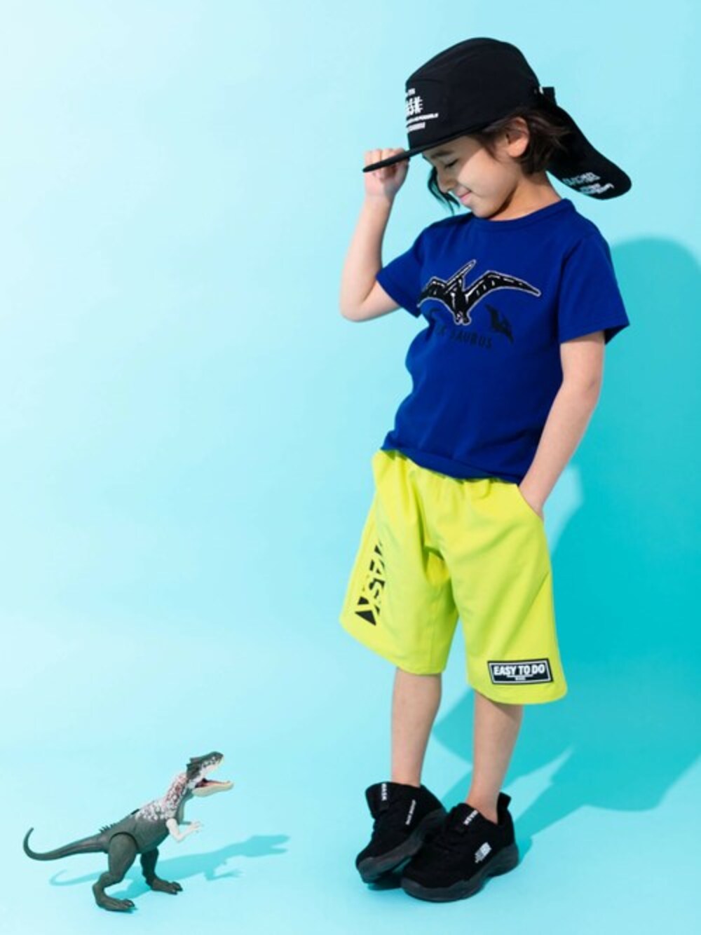 イエロー系のその他パンツ、ブルー系のTシャツ/カットソー、ブラック系のキャップを着用したキッズの春コーディネートの1枚目の写真