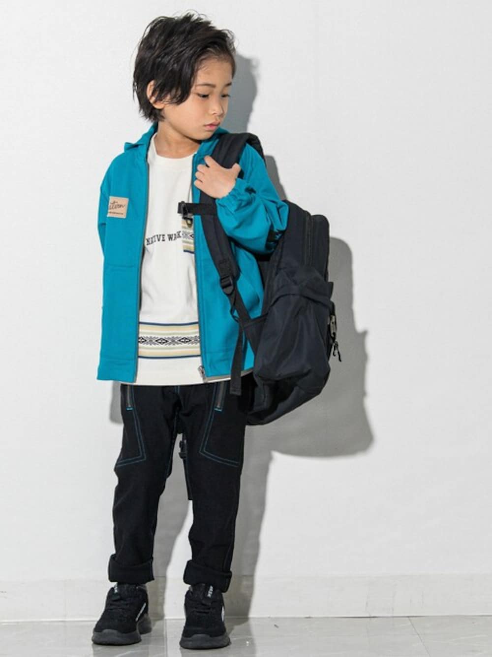 ブルー系のマウンテンパーカー、ブラック系のバックパック/リュック、ホワイト系のTシャツ/カットソーを着用したキッズの春コーディネートの1枚目の写真