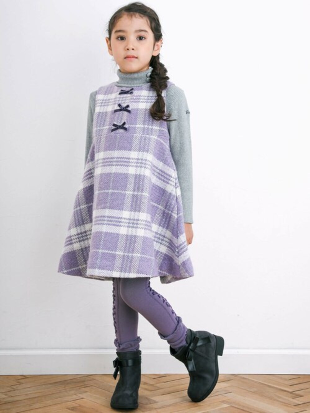 パープル系のジャンパースカート、グレー系のニット/セーター、グレー系のブーティを着用したキッズの秋コーディネートの1枚目の写真