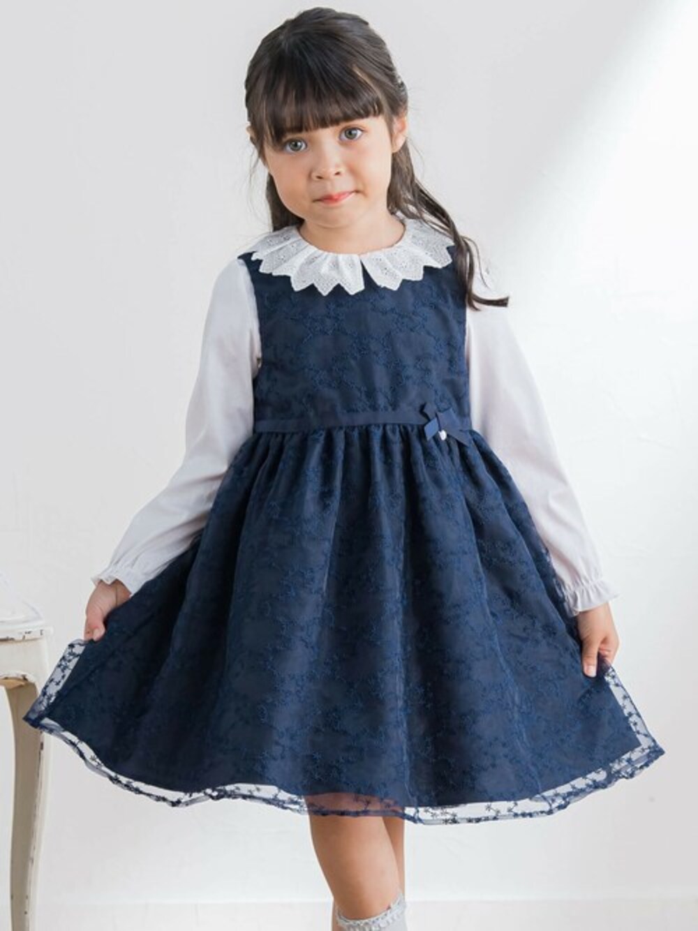 ホワイト系のシャツ/ブラウス、ブルー系のジャンパースカート、グレー系のソックス/靴下を着用したキッズの冬コーディネートの1枚目の写真