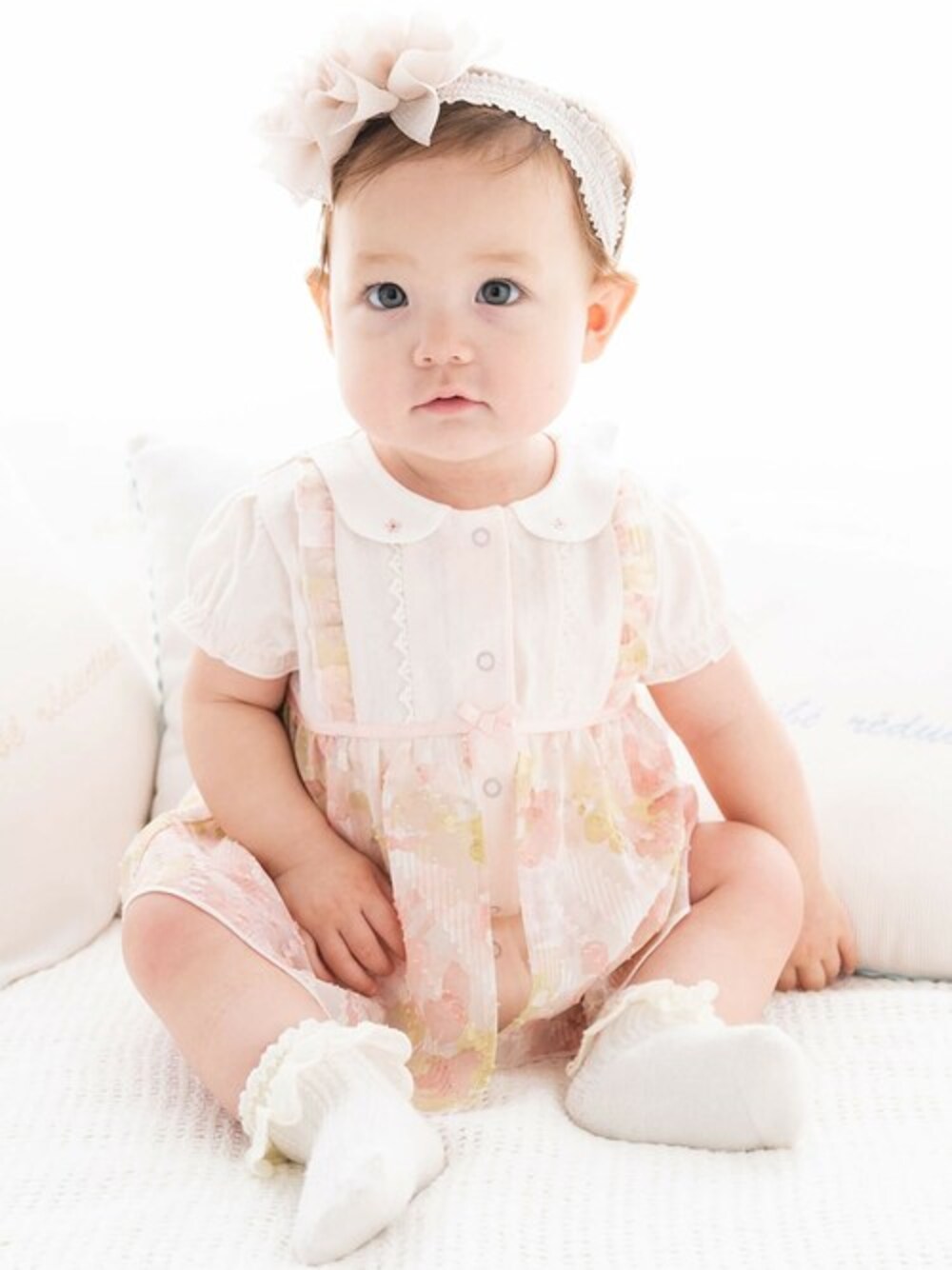 ピンク系のロンパース、ホワイト系のヘアバンドを着用したキッズの冬コーディネートの1枚目の写真