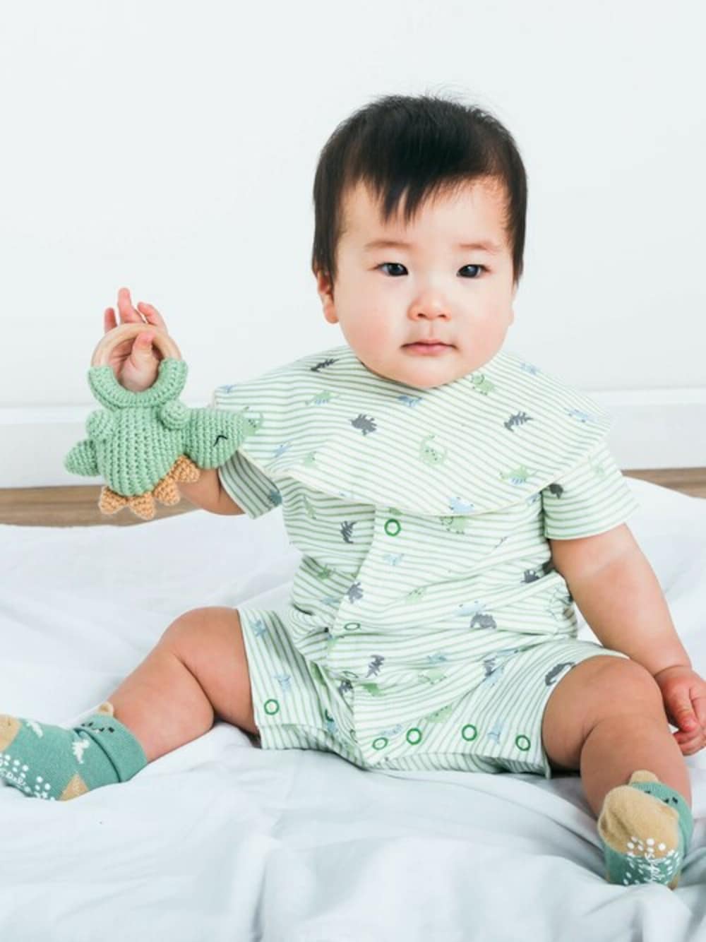 イエロー系のスタイ/よだれかけ、グリーン系のロンパース、グリーン系のその他ベビー用品を着用したキッズの春コーディネートの1枚目の写真