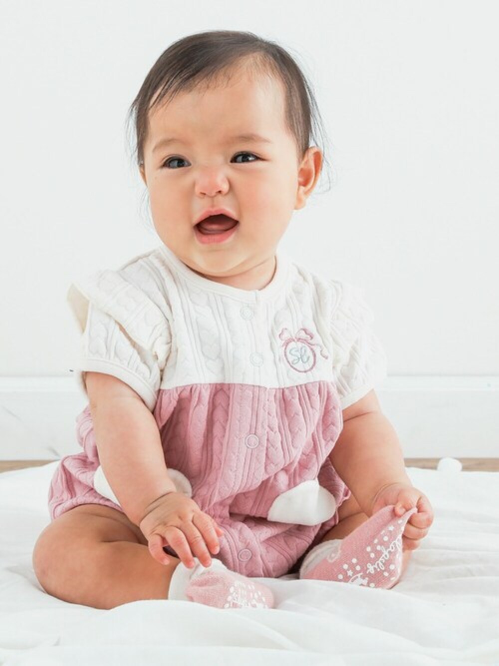 ピンク系のロンパース、ホワイト系のベビーシューズ/ベビーソックスを着用したキッズの春コーディネートの1枚目の写真