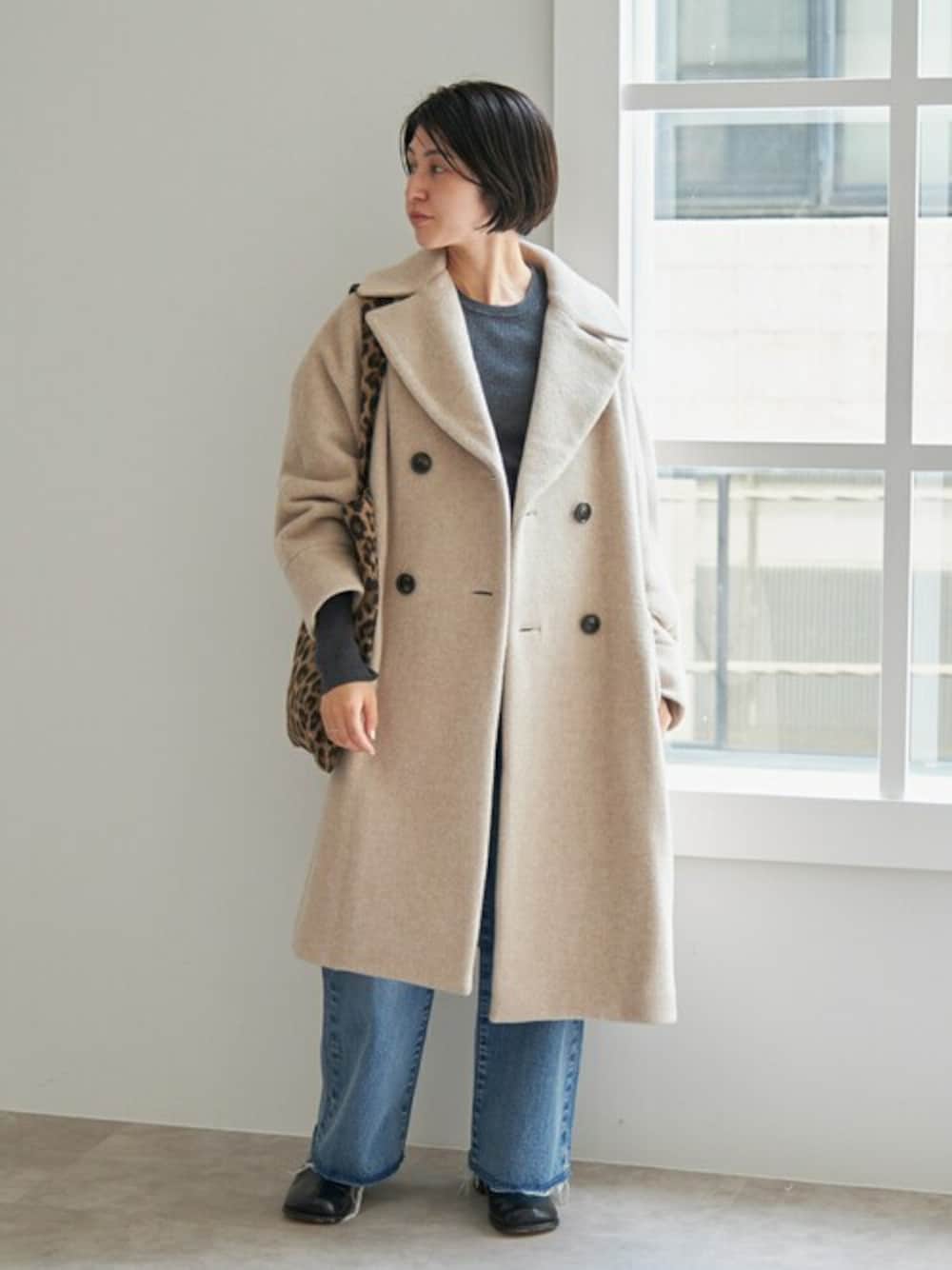 ベージュ系のピーコート、グレー系のニット/セーター、ブラック系のブーツを着用したレディースの冬コーディネートの1枚目の写真