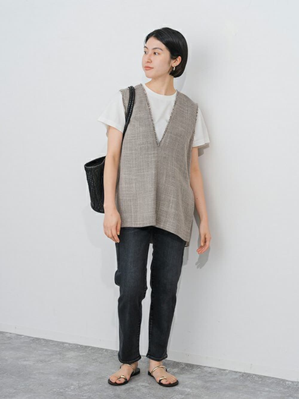 ブラック系のデニムパンツ、ブラック系のベスト、ホワイト系のTシャツ/カットソーを着用したレディースの春コーディネートの1枚目の写真