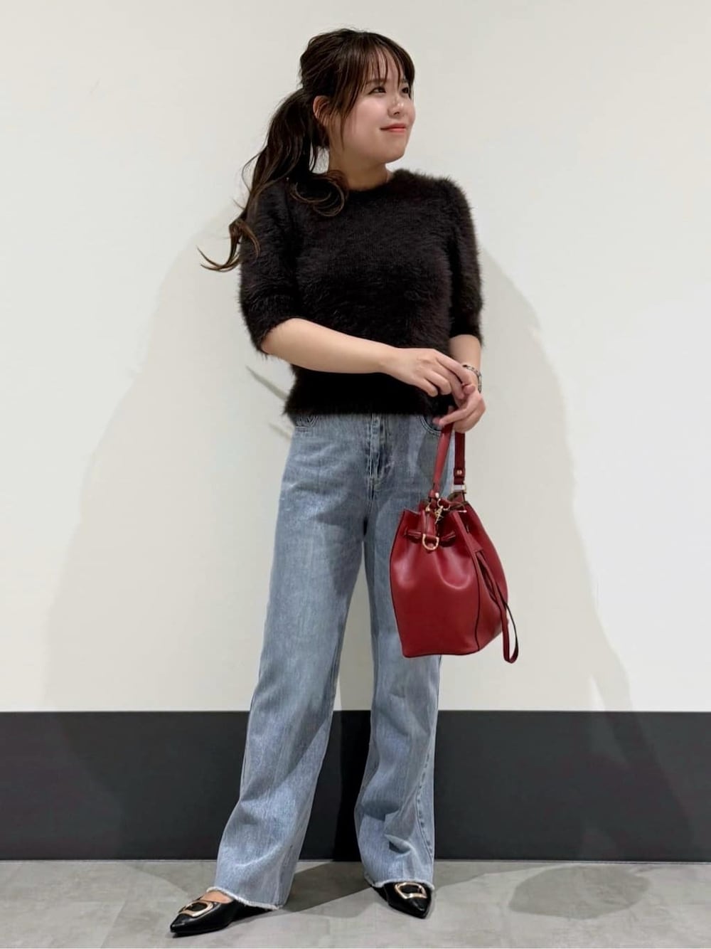 ブラウン系のニット/セーター、ブルー系のデニムパンツ、レッド系のショルダーバッグを着用したレディースの秋コーディネートの1枚目の写真