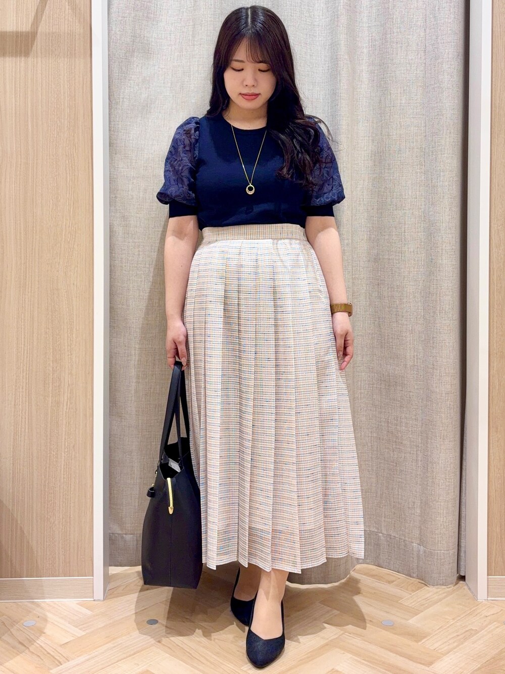 ブラック系のパンプス、ブラック系のトートバッグ、ブルー系のニット/セーターを着用したレディースの春コーディネートの1枚目の写真