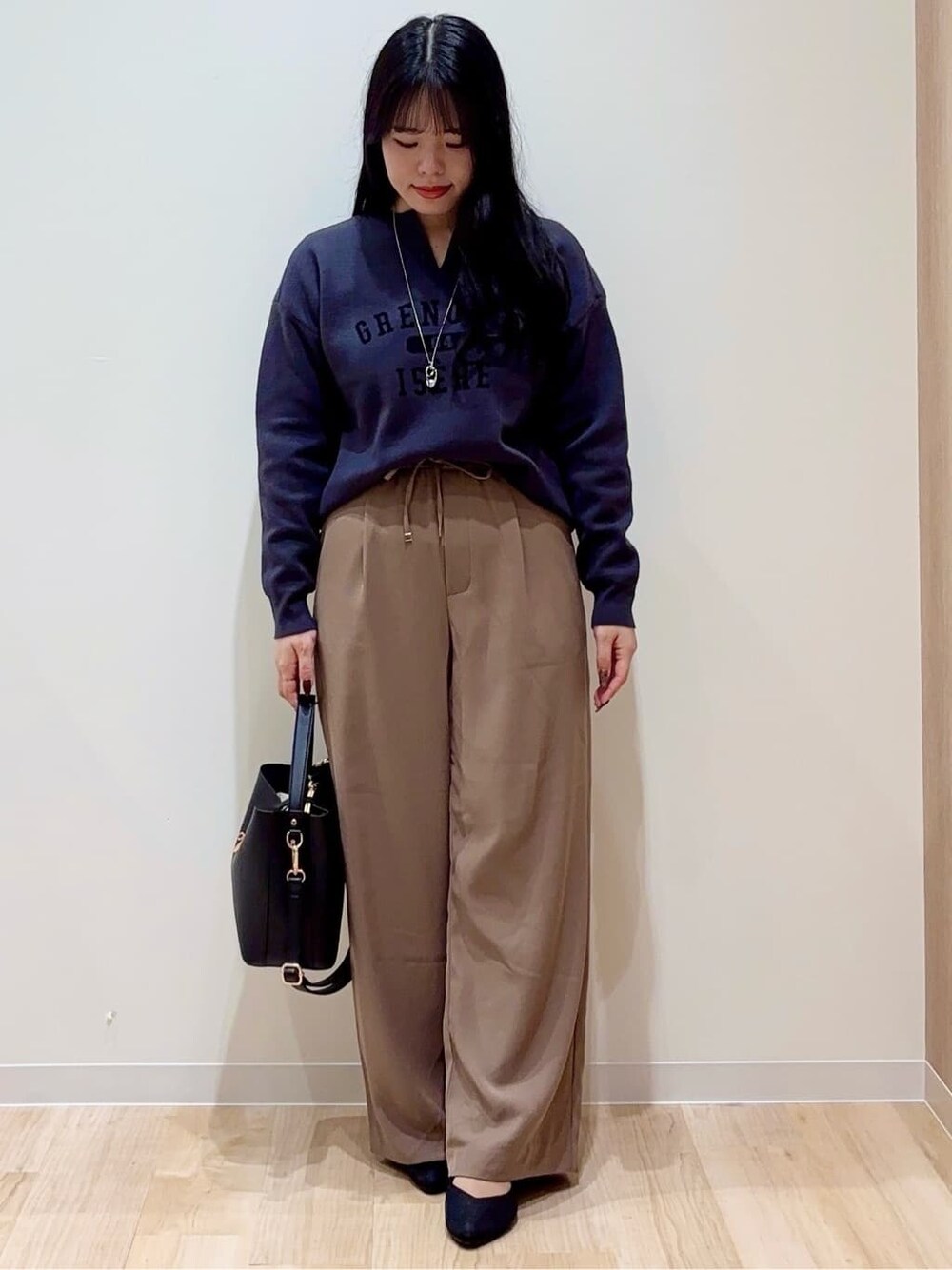グレー系のニット/セーター、ブラウン系のその他パンツ、ブラック系のショルダーバッグを着用したレディースの秋コーディネートの1枚目の写真