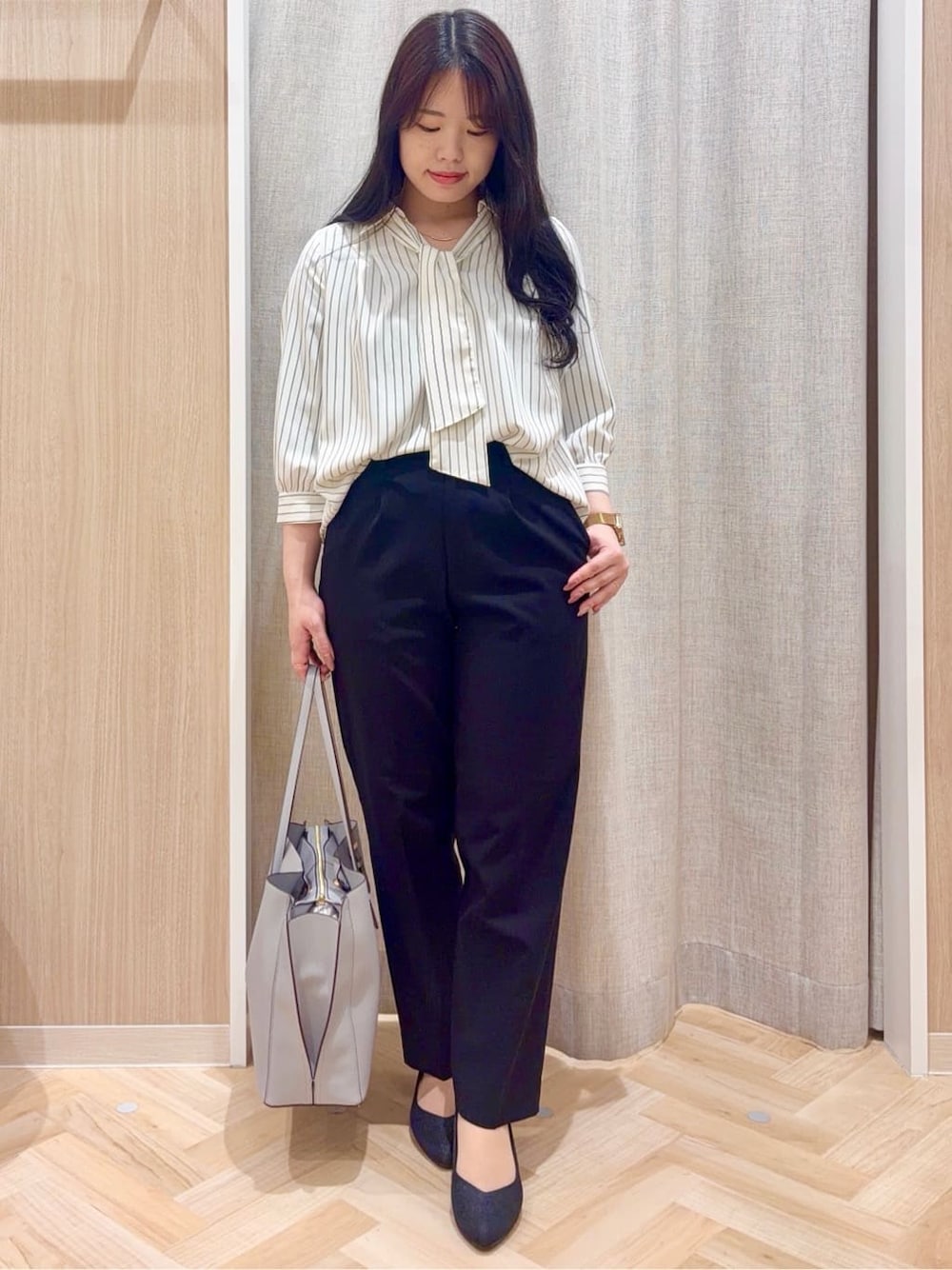 ブラック系のパンプス、ブルー系のトートバッグ、ブラック系のワンピースを着用したレディースの春コーディネートの1枚目の写真