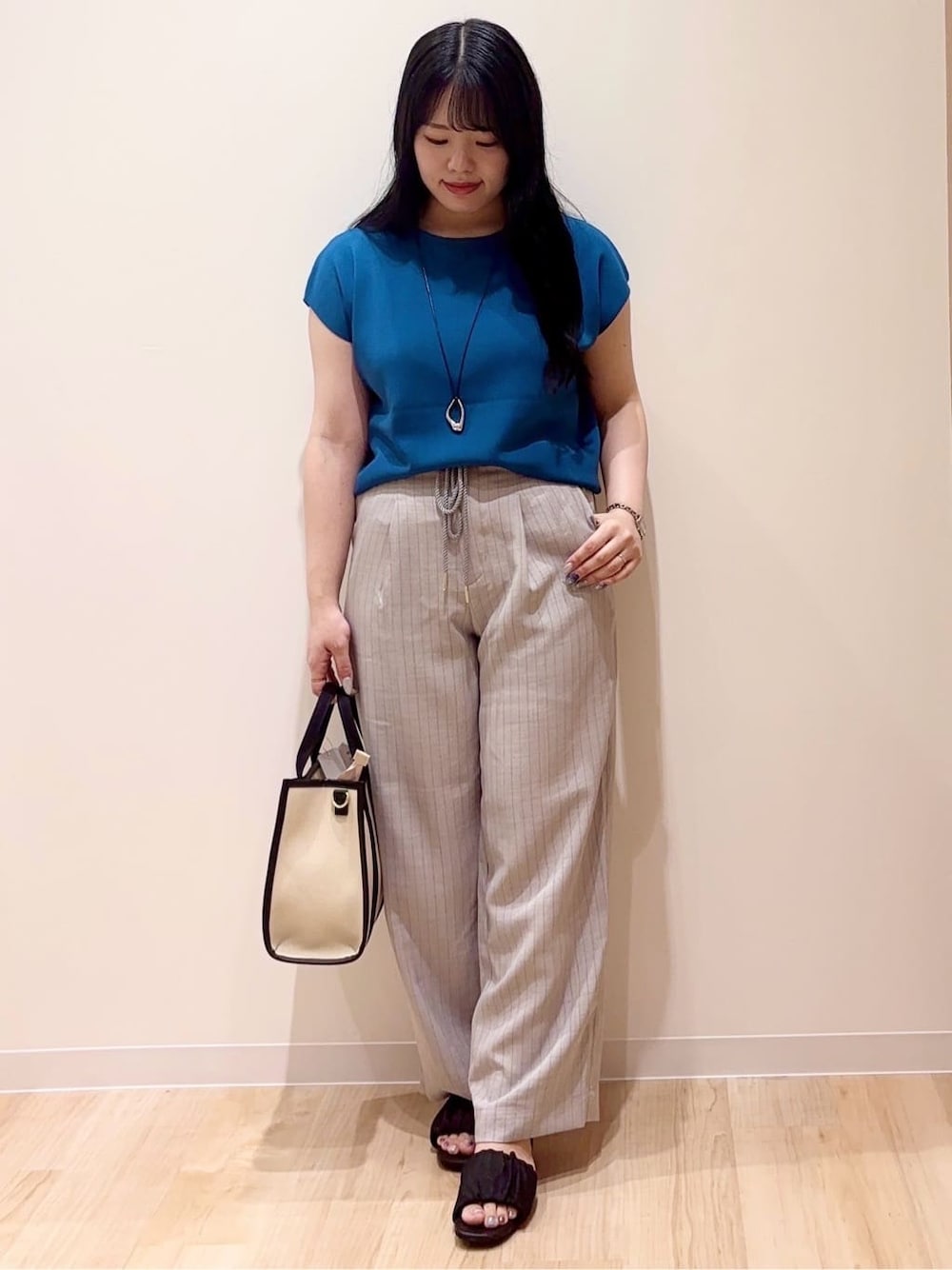 グレー系のその他パンツ、ブラック系のトートバッグ、シルバー系のネックレスを着用したレディースの夏コーディネートの1枚目の写真