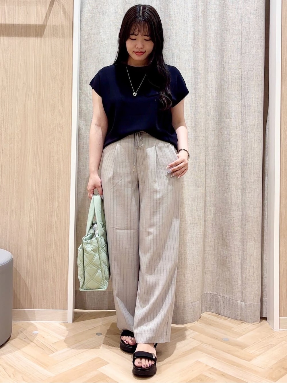 グレー系のその他パンツ、グリーン系のトートバッグ、シルバー系のネックレスを着用したレディースの夏コーディネートの1枚目の写真