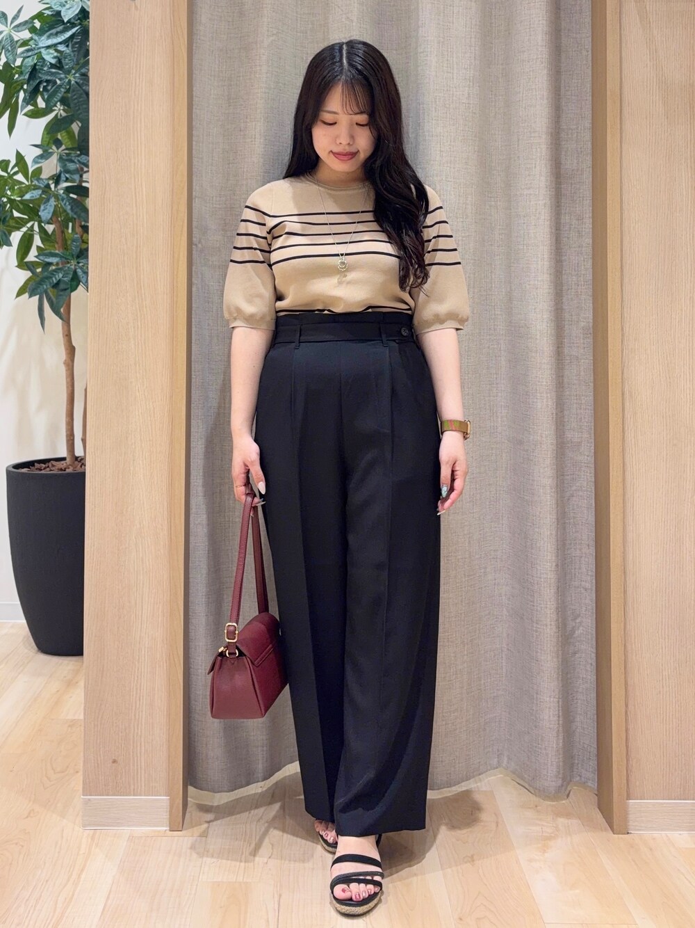 ベージュ系のニット/セーター、ブラック系のその他パンツ、レッド系のショルダーバッグを着用したレディースの夏コーディネートの1枚目の写真
