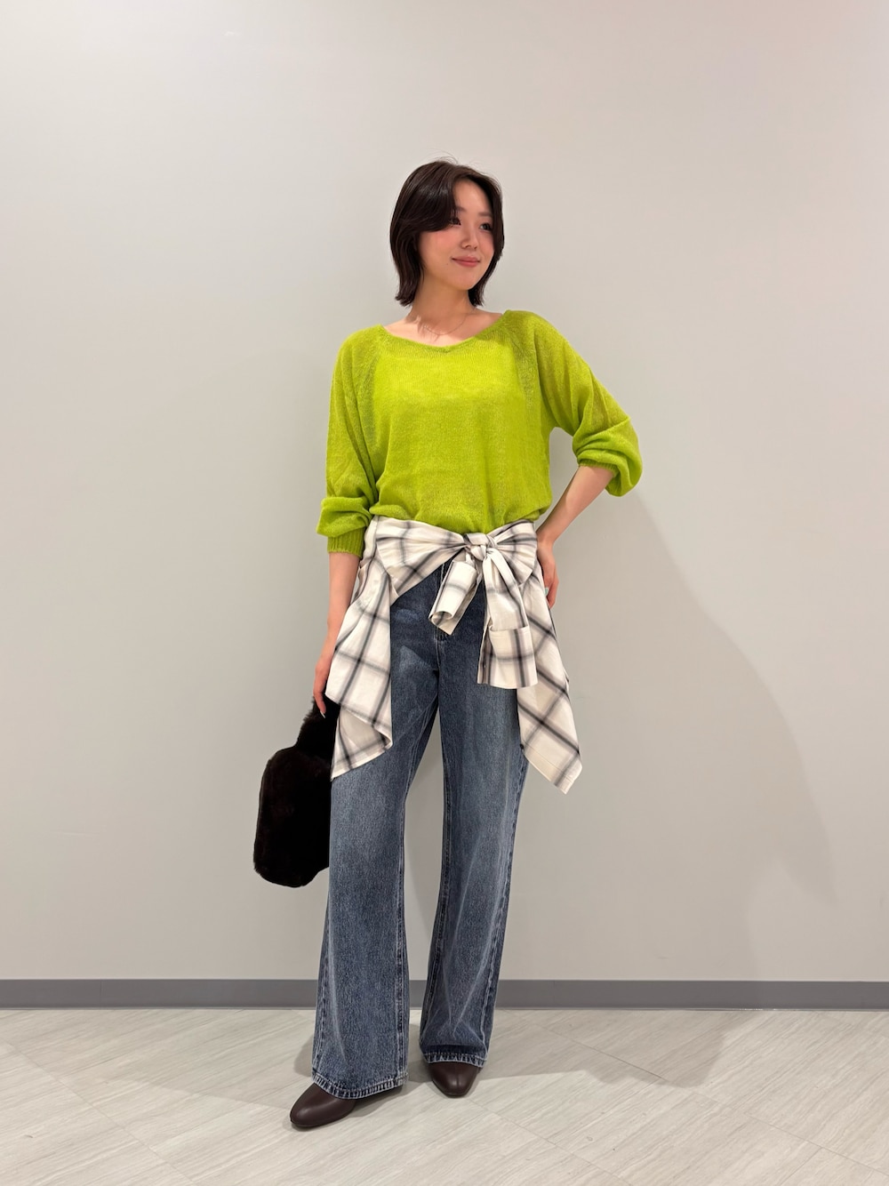 グリーン系のニット/セーター、ホワイト系のシャツ/ブラウス、ブルー系のデニムパンツを着用したレディースの秋コーディネートの1枚目の写真