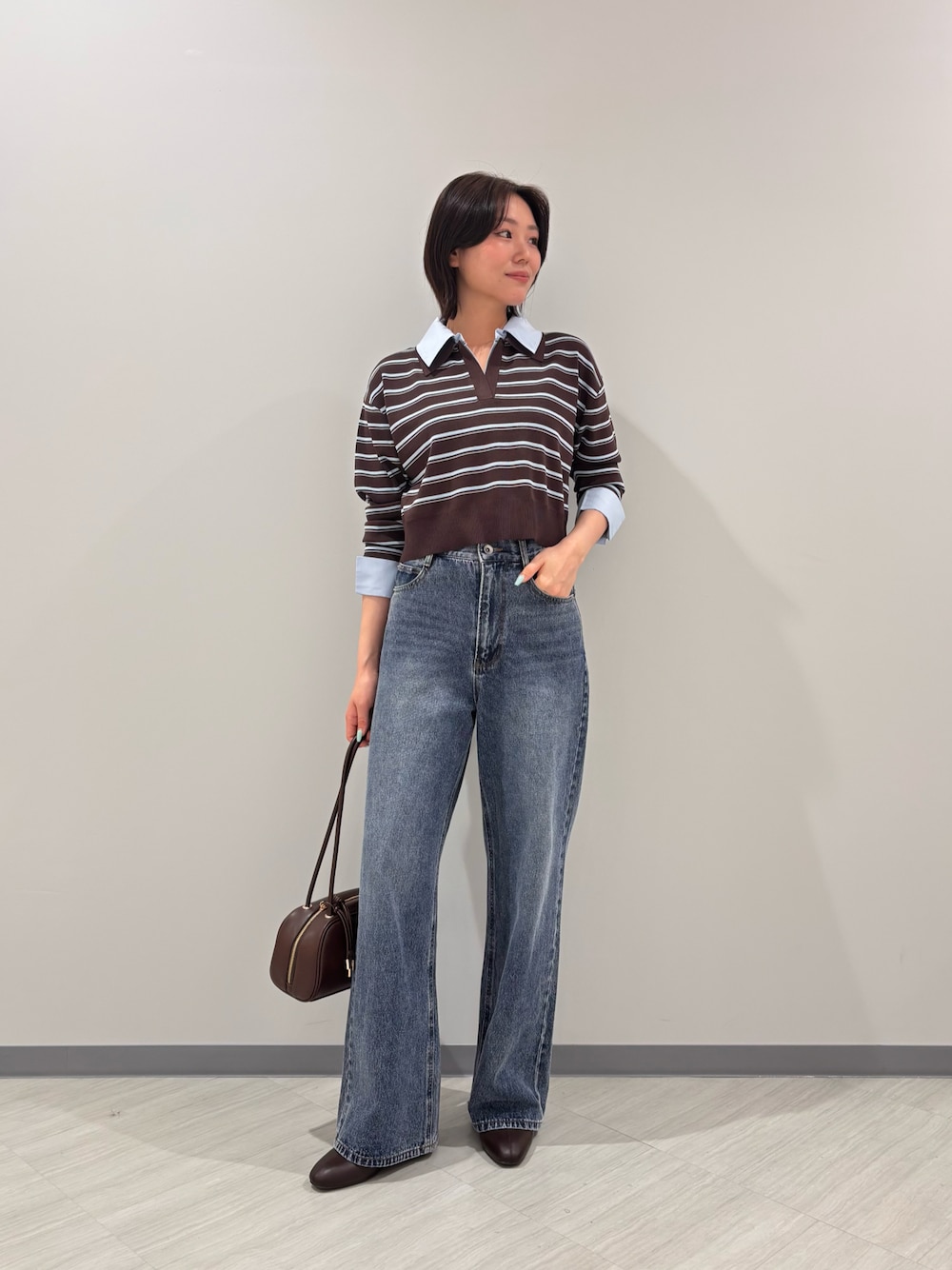 ブラウン系のニット/セーター、ブルー系のデニムパンツ、ブラック系のボストンバッグを着用したレディースの秋コーディネートの1枚目の写真