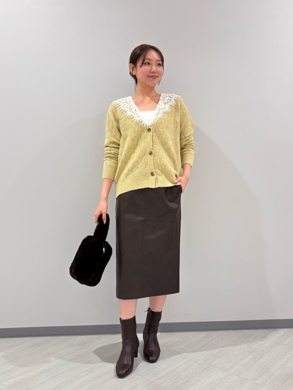 イエロー系のカーディガン/ボレロ、ブラウン系のスカート、ブラウン系のブーツを着用したレディースの秋コーディネートの1枚目の写真