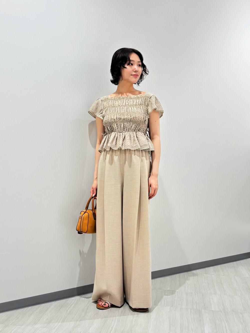 ベージュ系のシャツ/ブラウス、ベージュ系のその他パンツ、オレンジ系のボストンバッグを着用したレディースの夏コーディネートの1枚目の写真