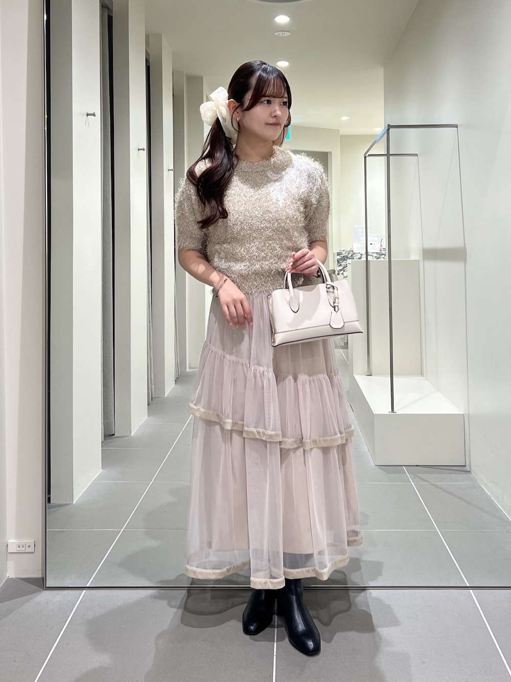 ベージュ系のニット/セーター、ベージュ系のスカート、ホワイト系のトートバッグを着用したレディースの夏コーディネートの1枚目の写真