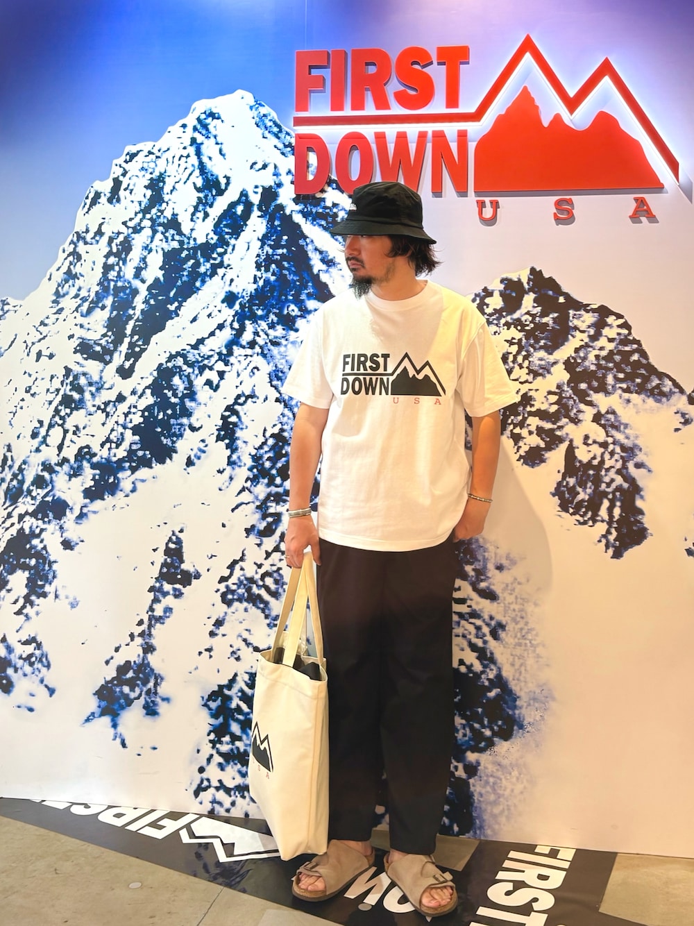 ホワイト系のTシャツ/カットソー、ブルー系のその他パンツ、ホワイト系のトートバッグを着用したメンズの夏コーディネートの1枚目の写真