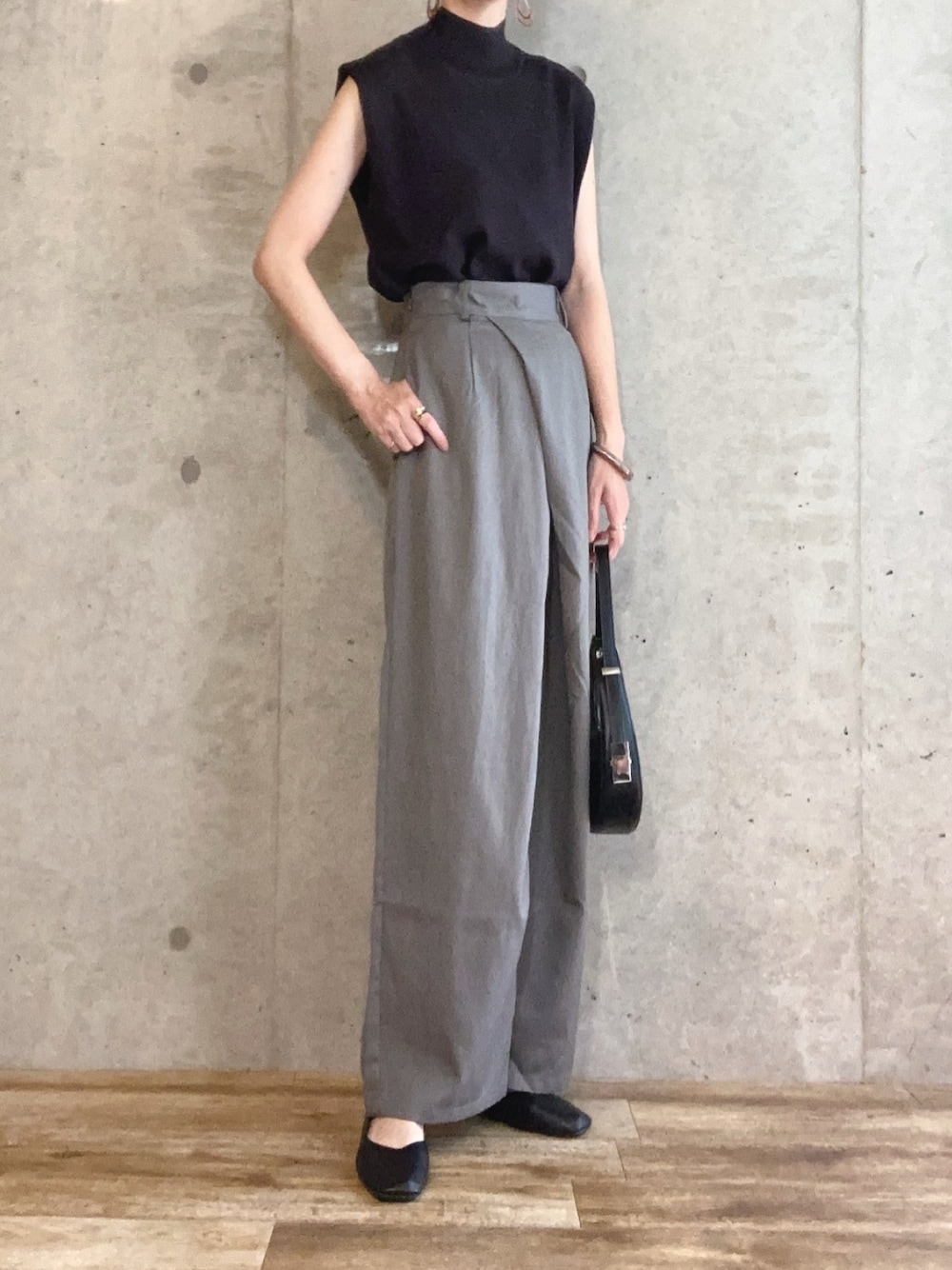 ブラック系のニット/セーター、グレー系のスラックス、ブラック系のハンドバッグを着用したレディースの夏コーディネートの1枚目の写真