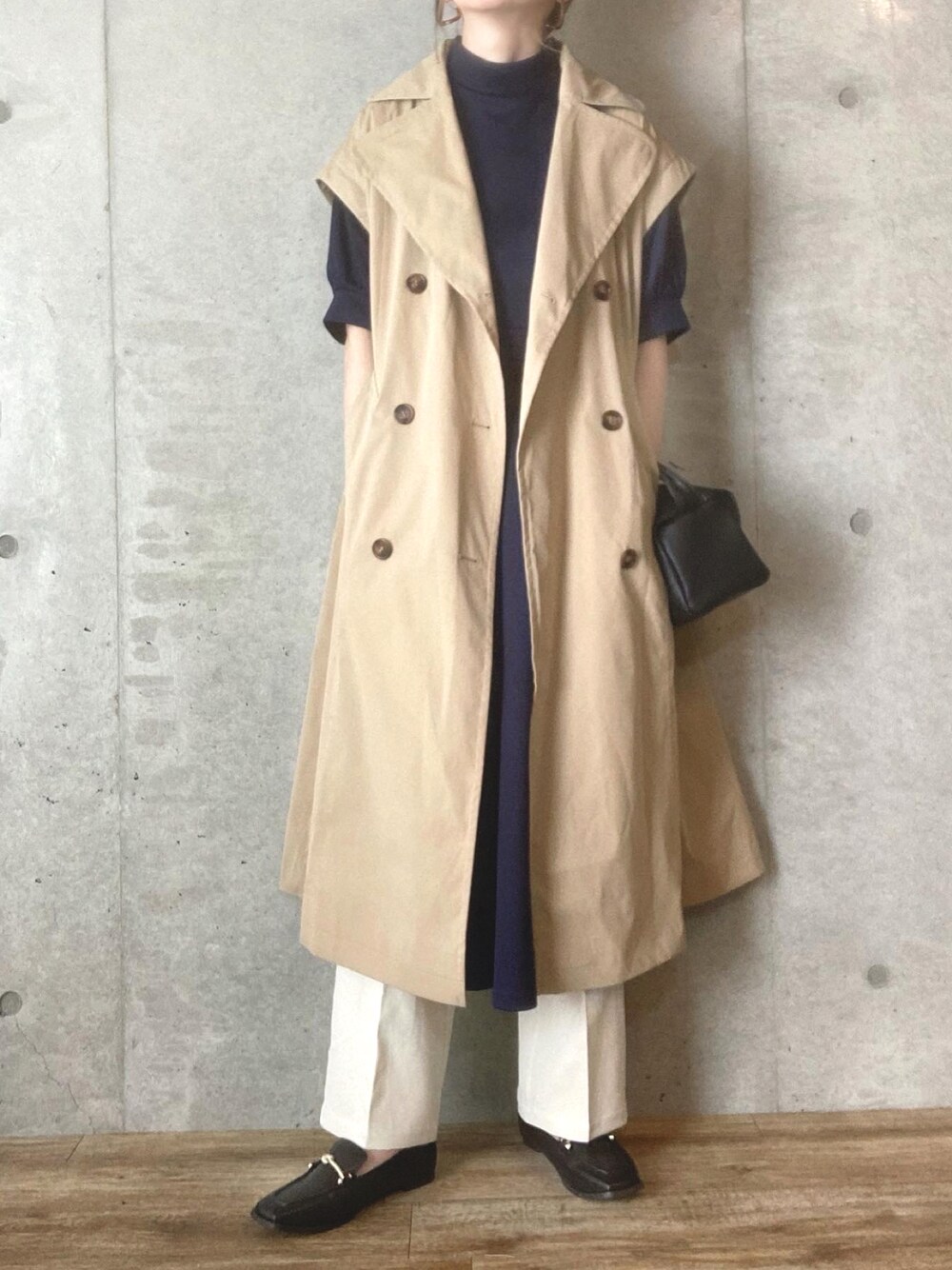 ベージュ系のトレンチコート、ブラック系のショルダーバッグ、ホワイト系のスラックスを着用したレディースの春コーディネートの1枚目の写真