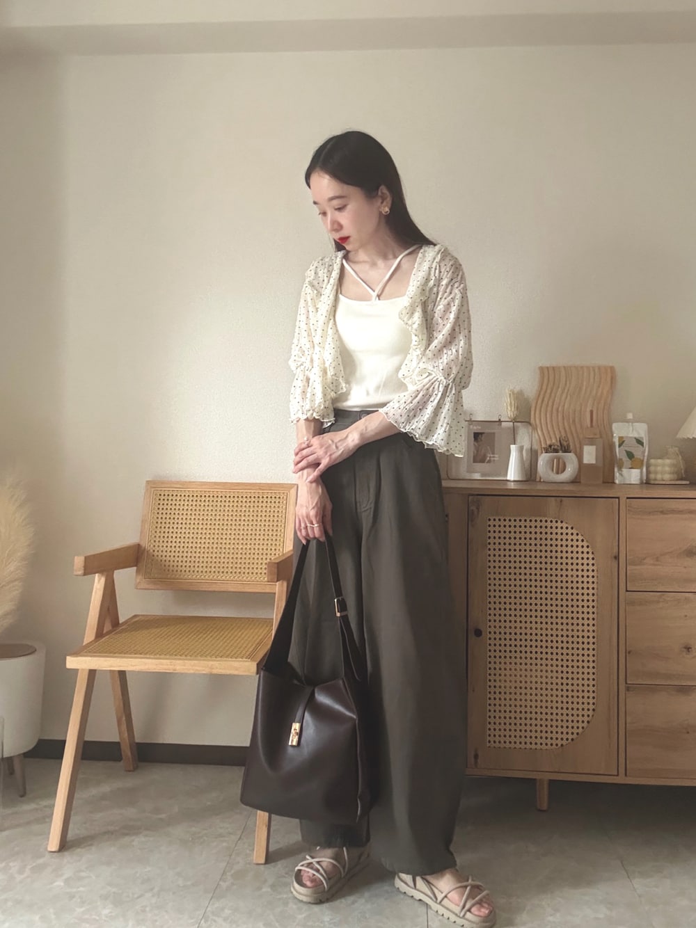 ホワイト系のカーディガン/ボレロ、ホワイト系のキャミソール、ブラウン系のデニムパンツを着用したレディースの夏コーディネートの1枚目の写真
