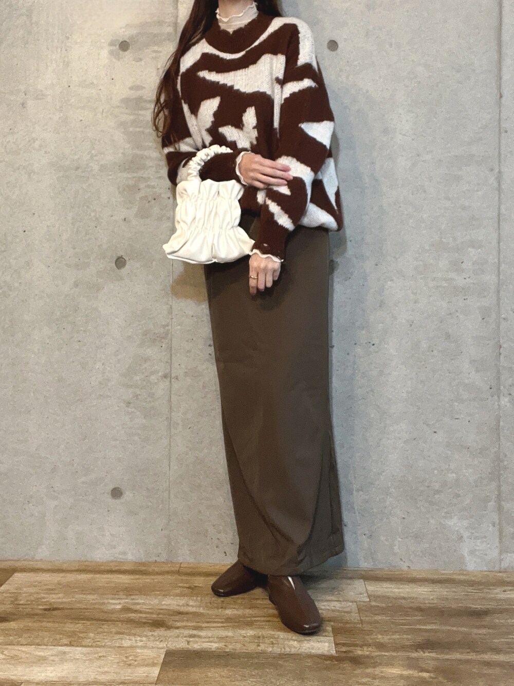 ブラウン系のニット/セーター、ホワイト系のショルダーバッグ、ブラウン系のワンピースを着用したレディースの春コーディネートの1枚目の写真