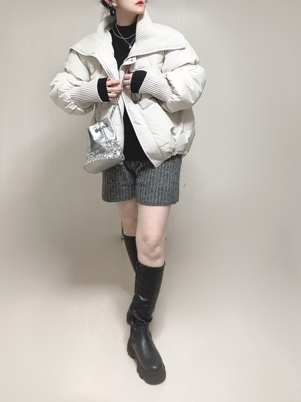 ホワイト系のダウンジャケット/コート、ブラック系のニット/セーター、ブラック系のブーツを着用したレディースの冬コーディネートの1枚目の写真