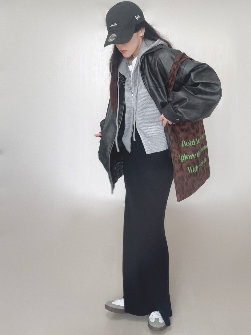 グレー系のパーカー、ブラック系のブルゾン、ブラウン系のトートバッグを着用したレディースの冬コーディネートの1枚目の写真