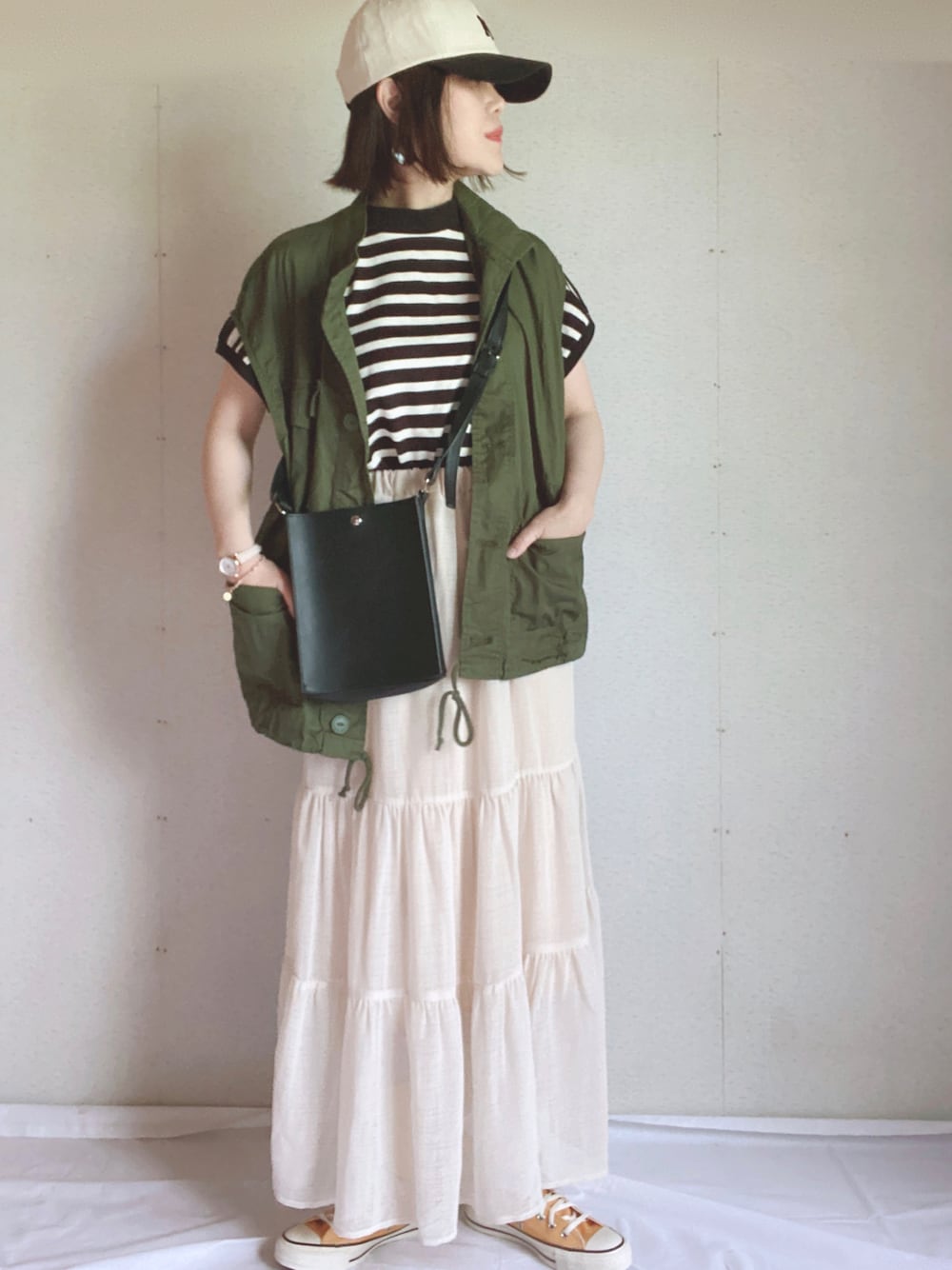 ホワイト系のTシャツ/カットソー、ホワイト系のスカート、ブラック系のショルダーバッグを着用したレディースの春コーディネートの1枚目の写真