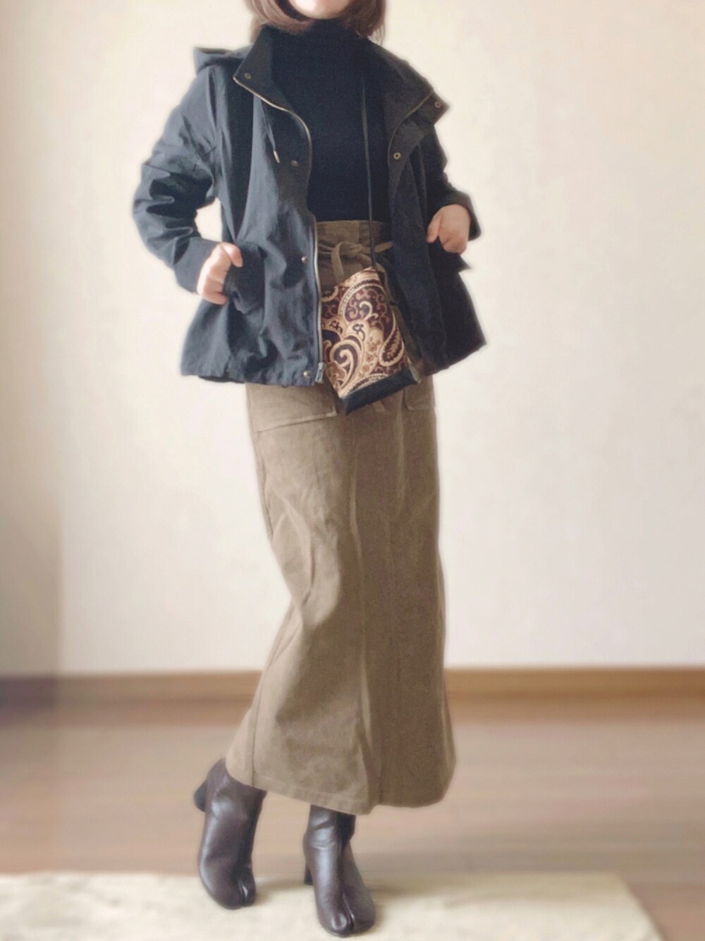 ブラック系のマウンテンパーカー、ブラウン系のブーツ、ベージュ系のスカートを着用したレディースの秋コーディネートの1枚目の写真