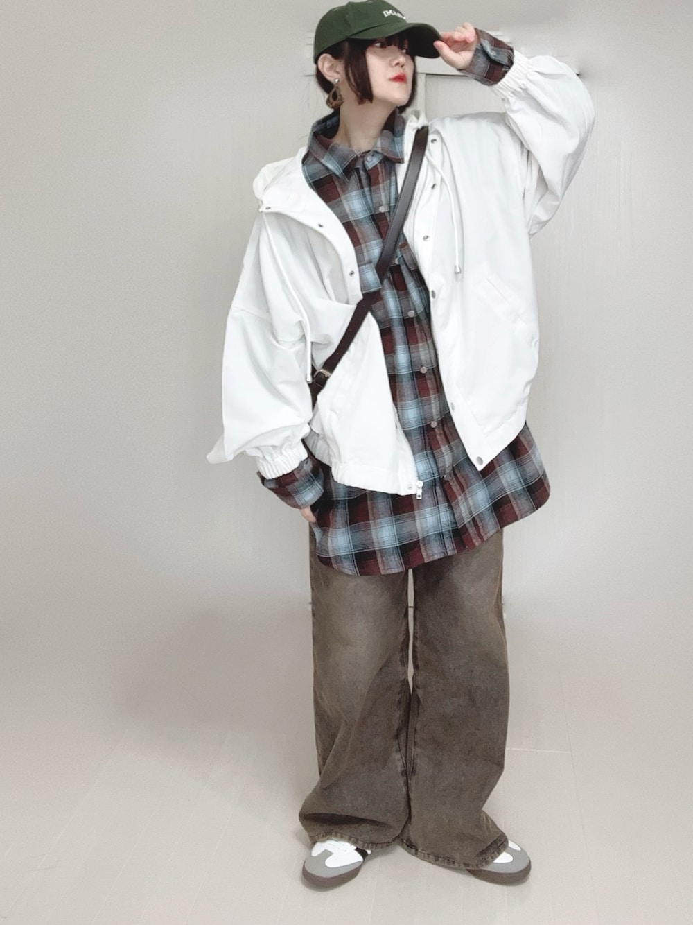 ホワイト系のマウンテンパーカー、ブラウン系のシャツ/ブラウス、ブラック系のデニムパンツを着用したレディースの春コーディネートの1枚目の写真