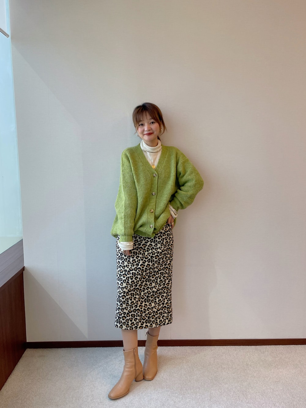 グリーン系のアンサンブル、ベージュ系のスカートを着用したレディースの冬コーディネートの1枚目の写真