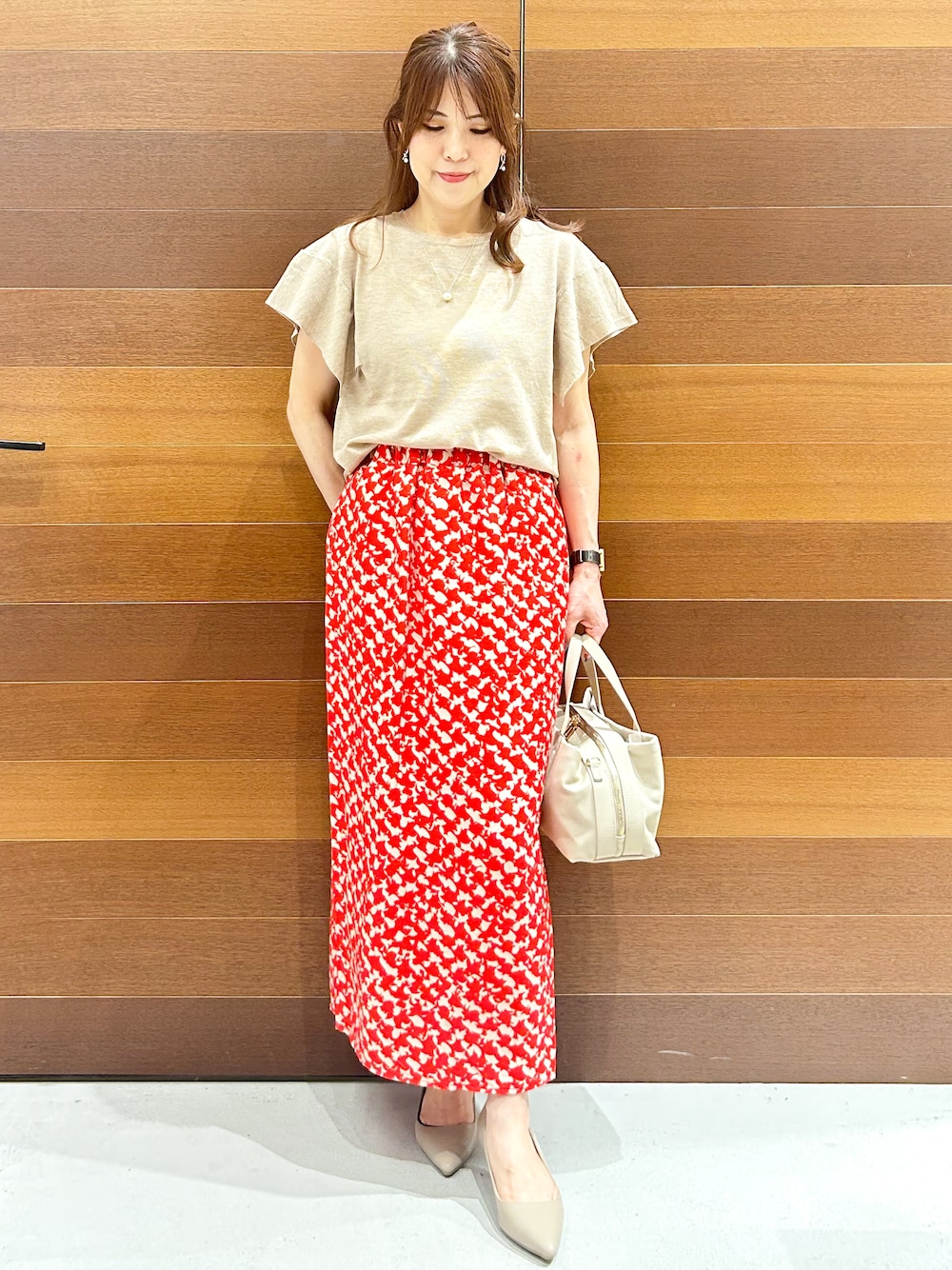 ベージュ系のニット/セーター、レッド系のスカート、グレー系のボストンバッグを着用したレディースの夏コーディネートの1枚目の写真