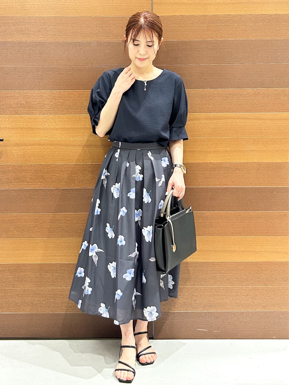 ブルー系のシャツ/ブラウス、グレー系のスカート、ブラック系のトートバッグを着用したレディースの夏コーディネートの1枚目の写真