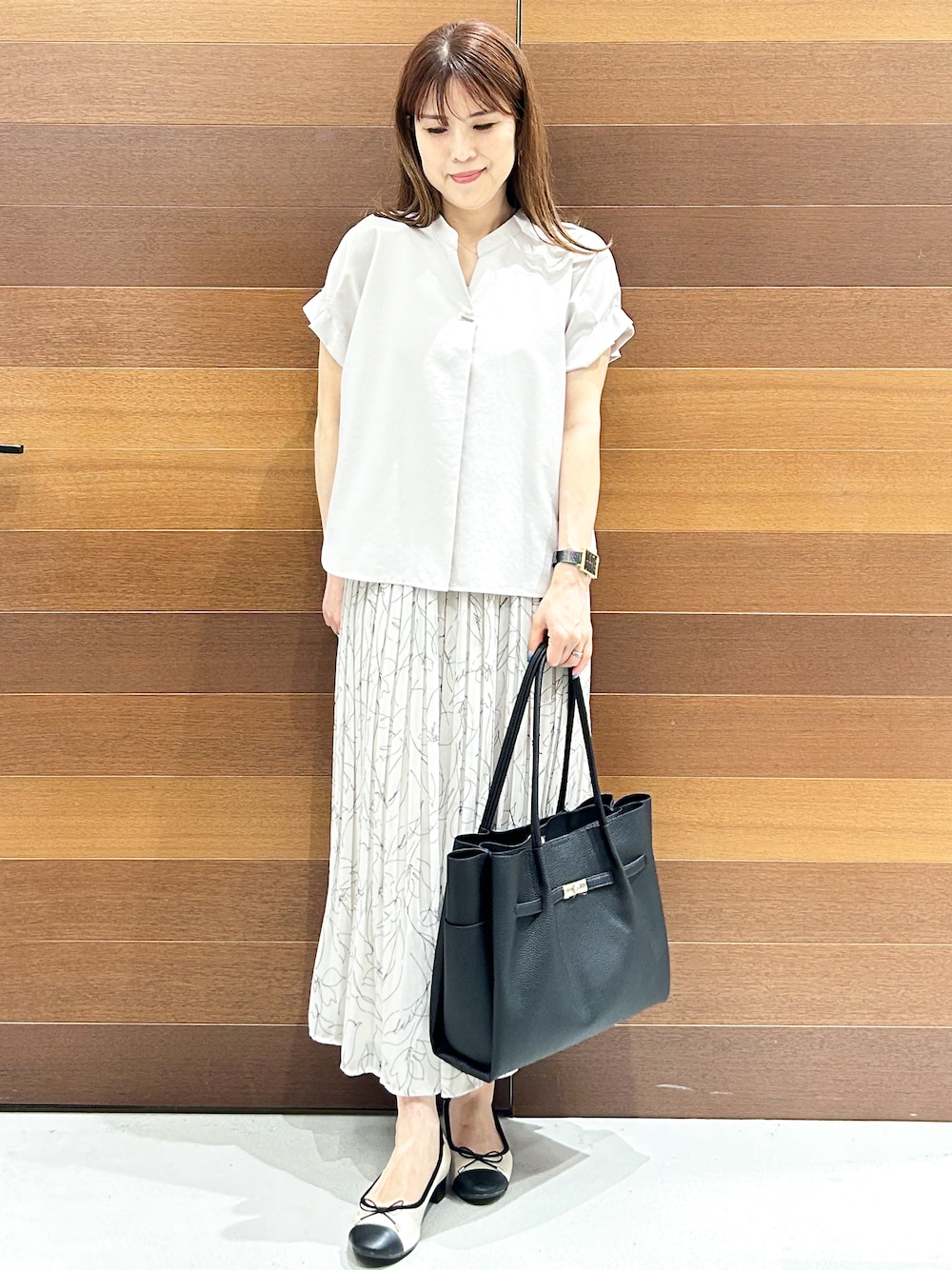 ベージュ系のシャツ/ブラウス、ブラック系のトートバッグ、ベージュ系のパンプスを着用したレディースの夏コーディネートの1枚目の写真